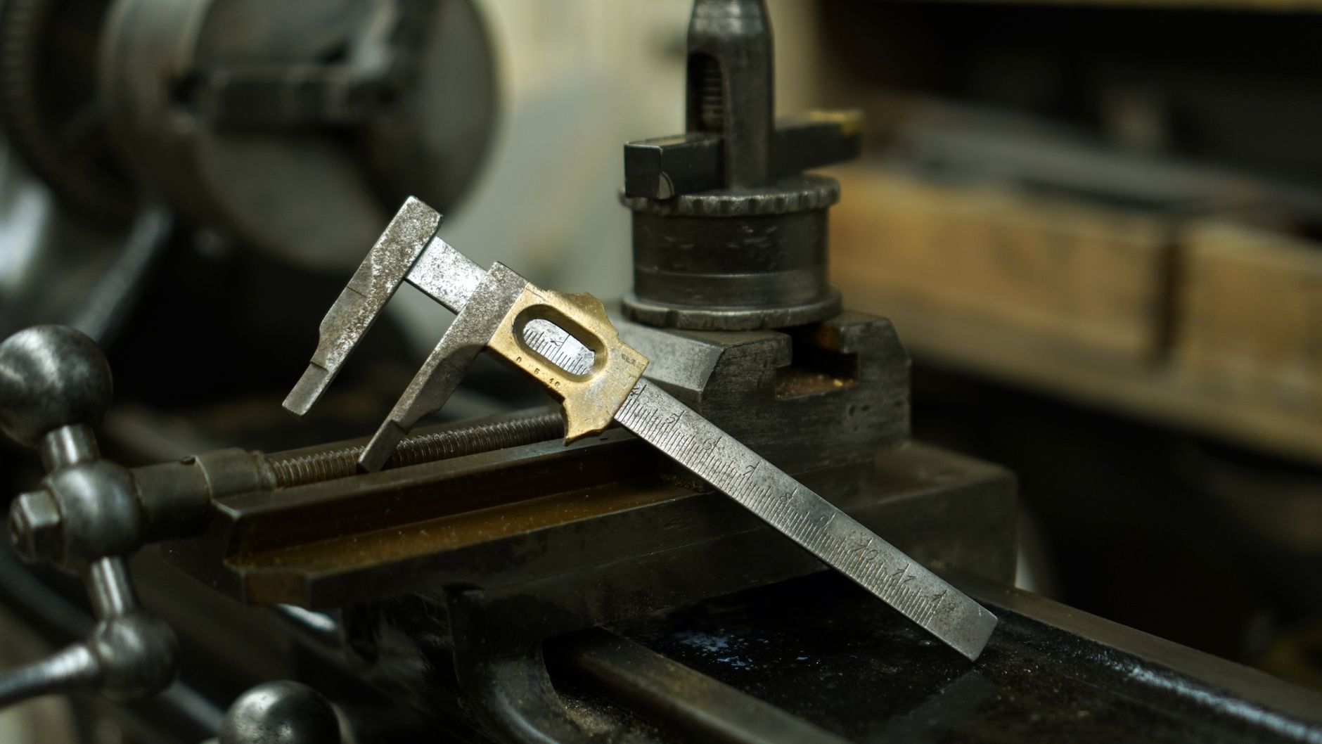 A machinist measures a finished metal component to verify its dimensions during precision production.