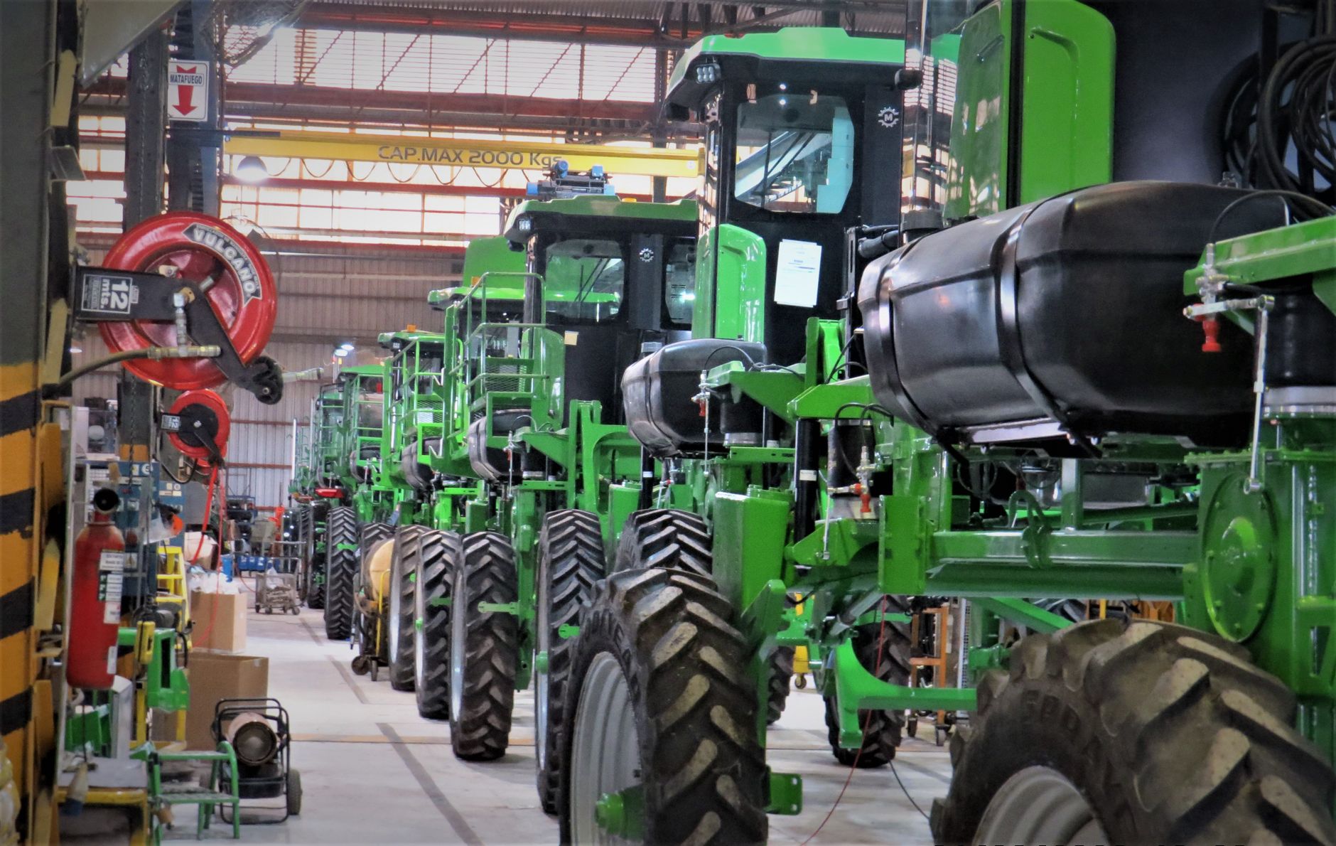 Workers assemble agricultural machinery on a busy factory floor.