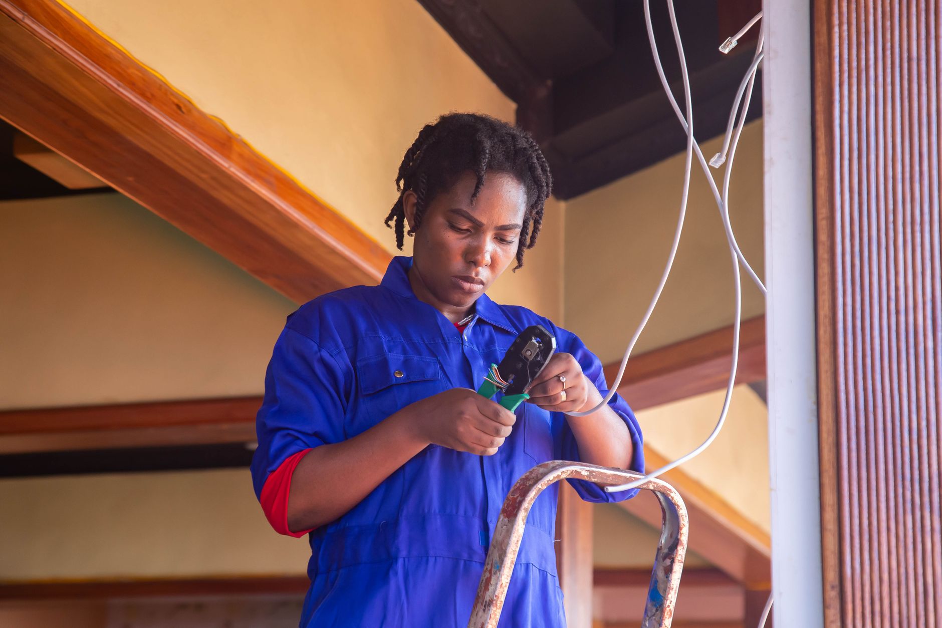 A technician inspecting electrical wiring concealed above a commercial ceiling.