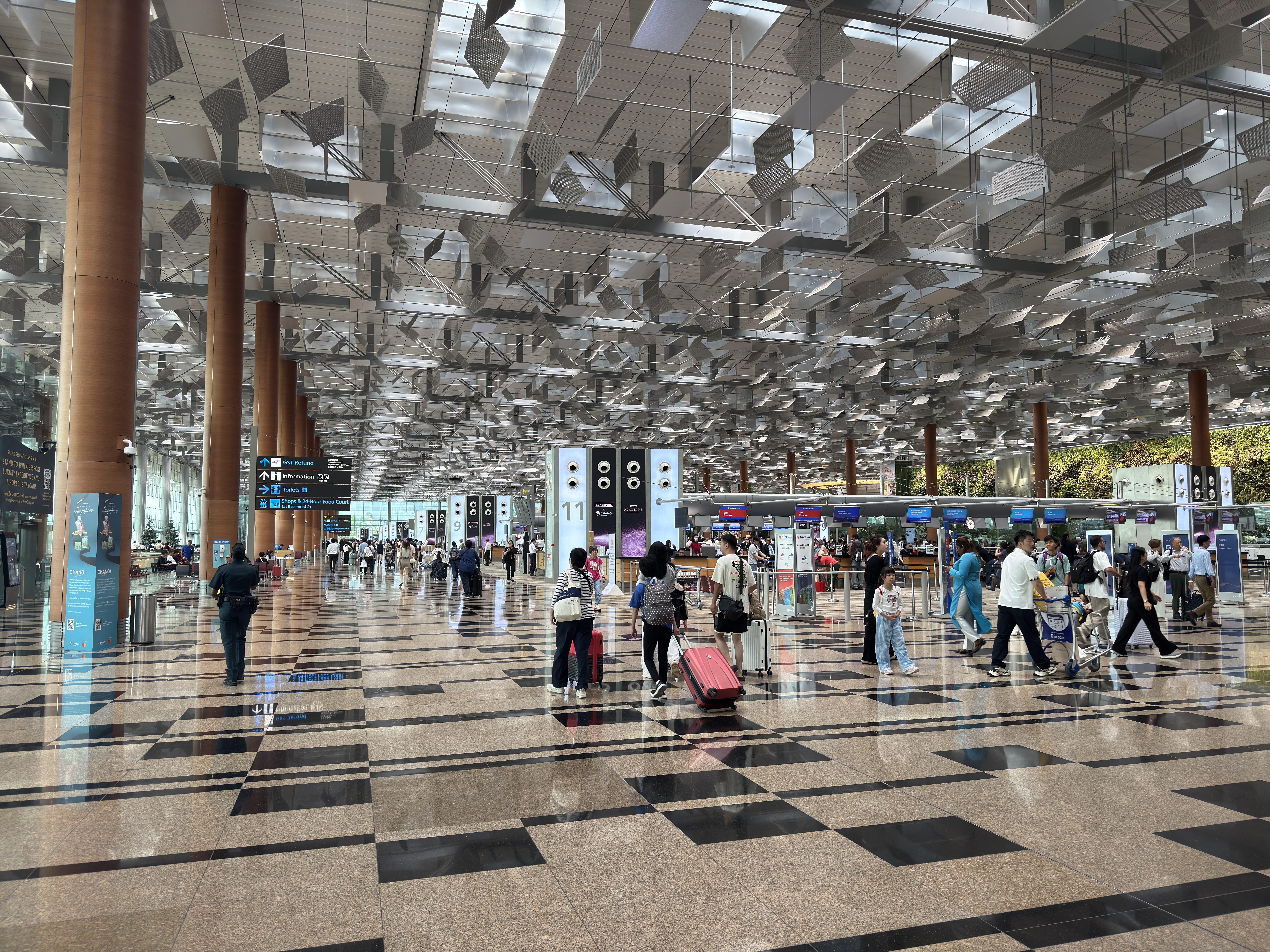 A spacious Changi Airport passenger concourse beneath an expansive paneled ceiling.