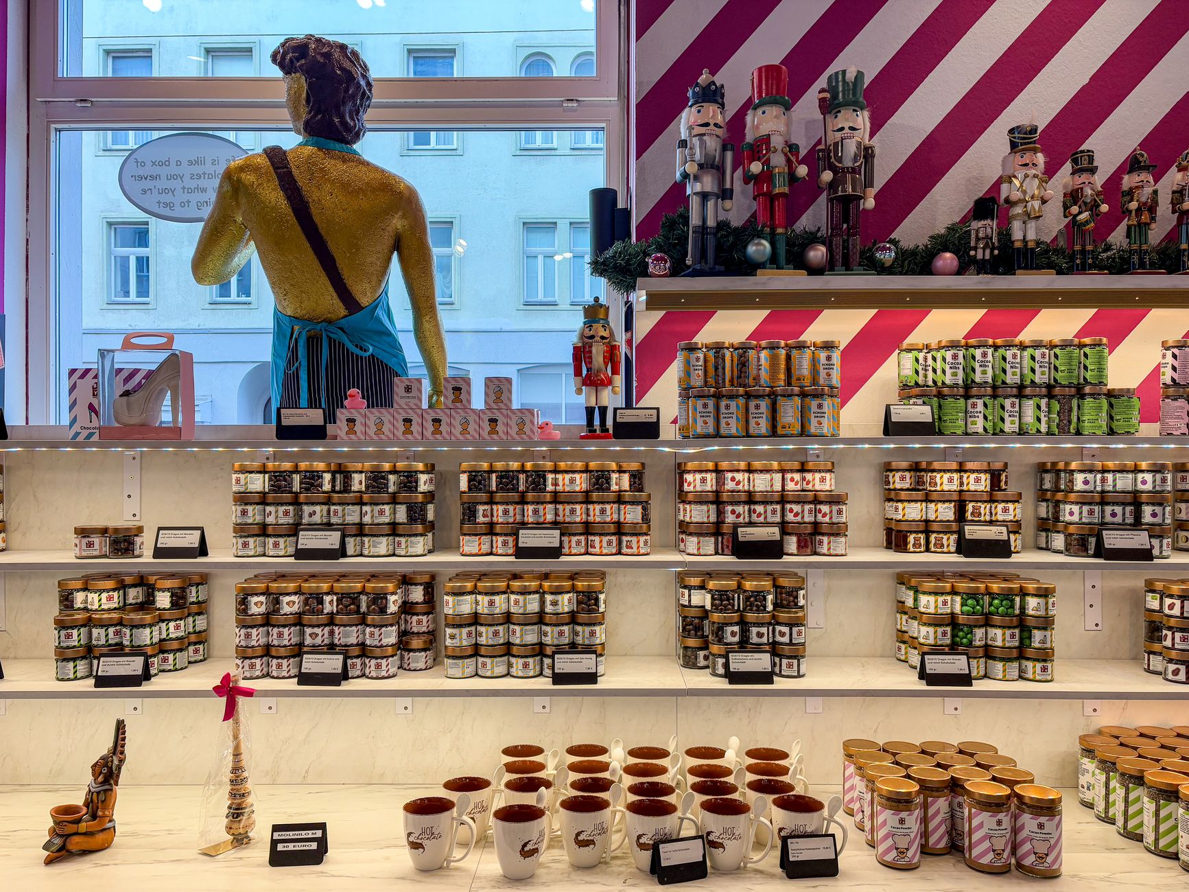 A colorful chocolate shop display presents boxed sweets to passing customers.
