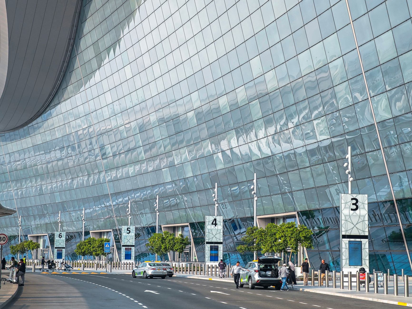 Cars pulling up at an airport drop-off area, echoing the transfer-bay handoff before autonomous storage begins.