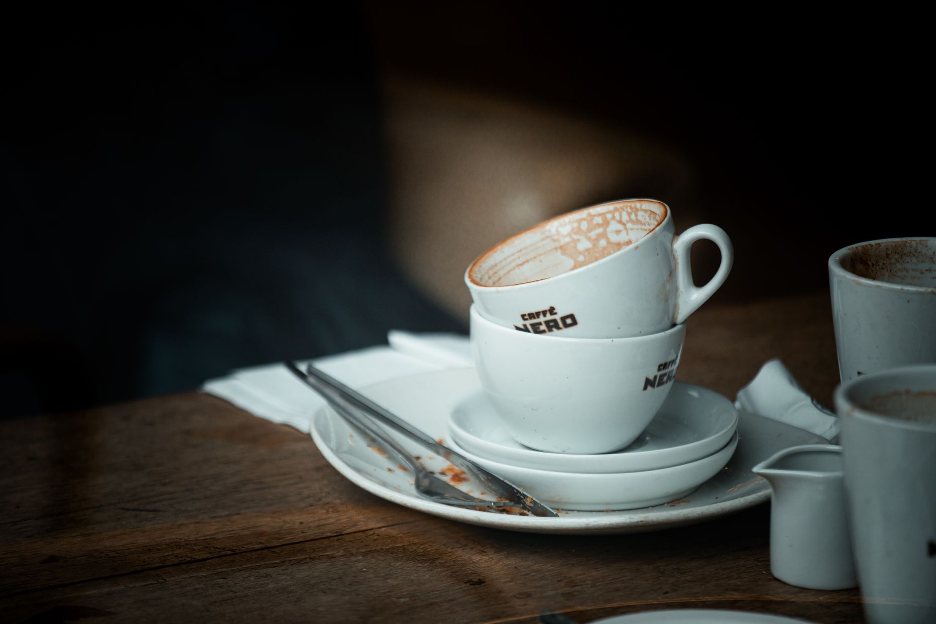 Used plates and cups are stacked for collection during a busy restaurant service.