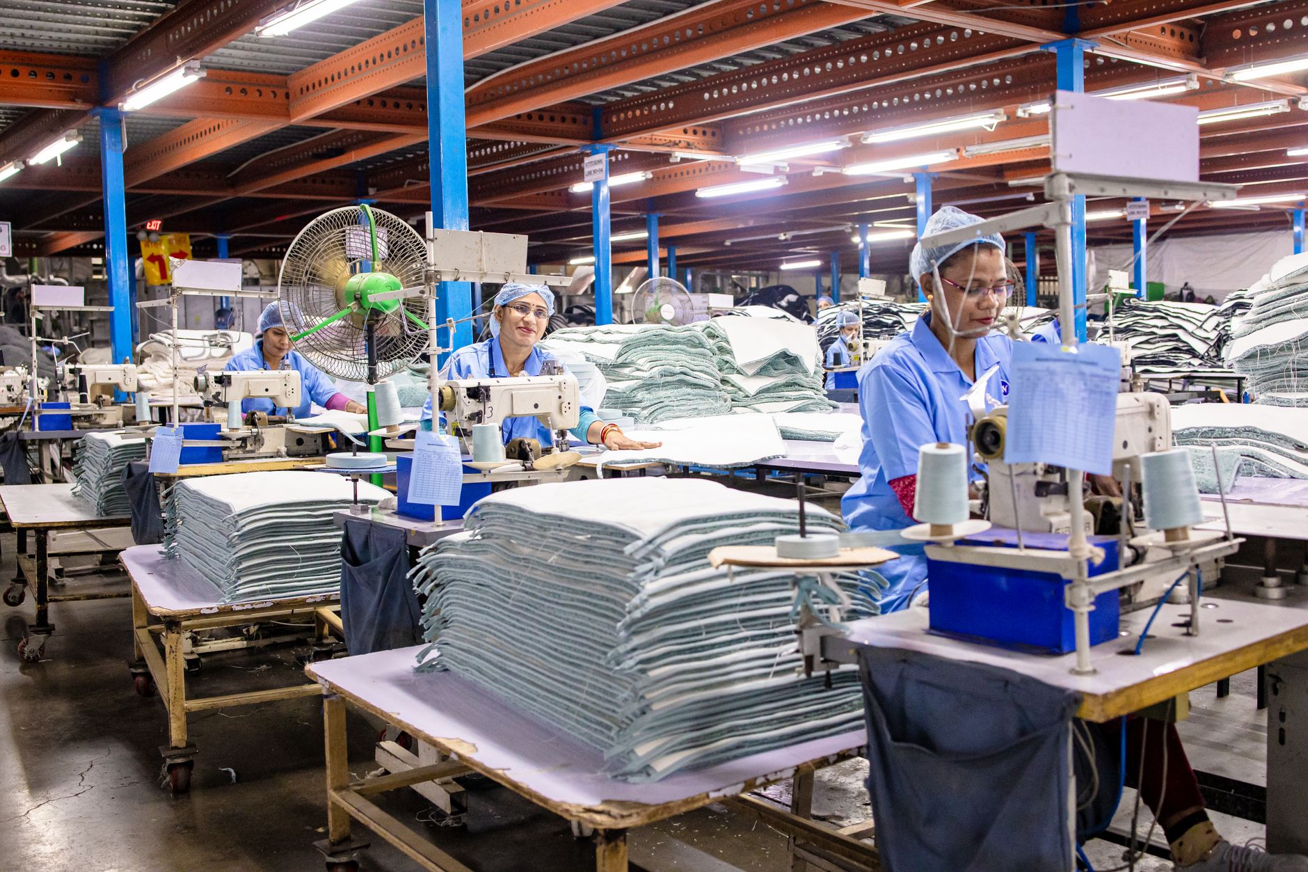 Workers and equipment along a bright manufacturing line where parts move toward assembly stations.