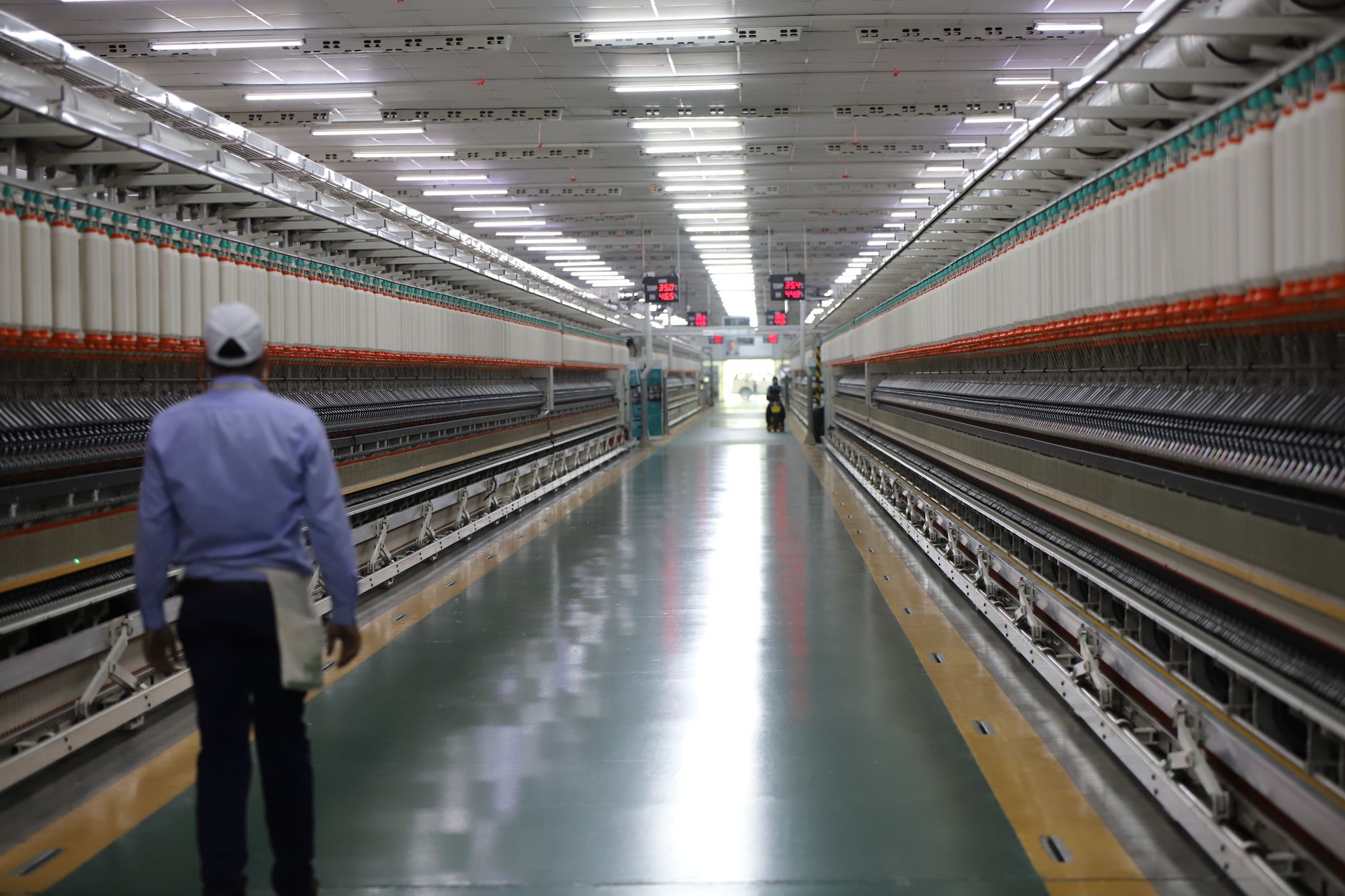 An employee walks a long factory corridor while moving materials.