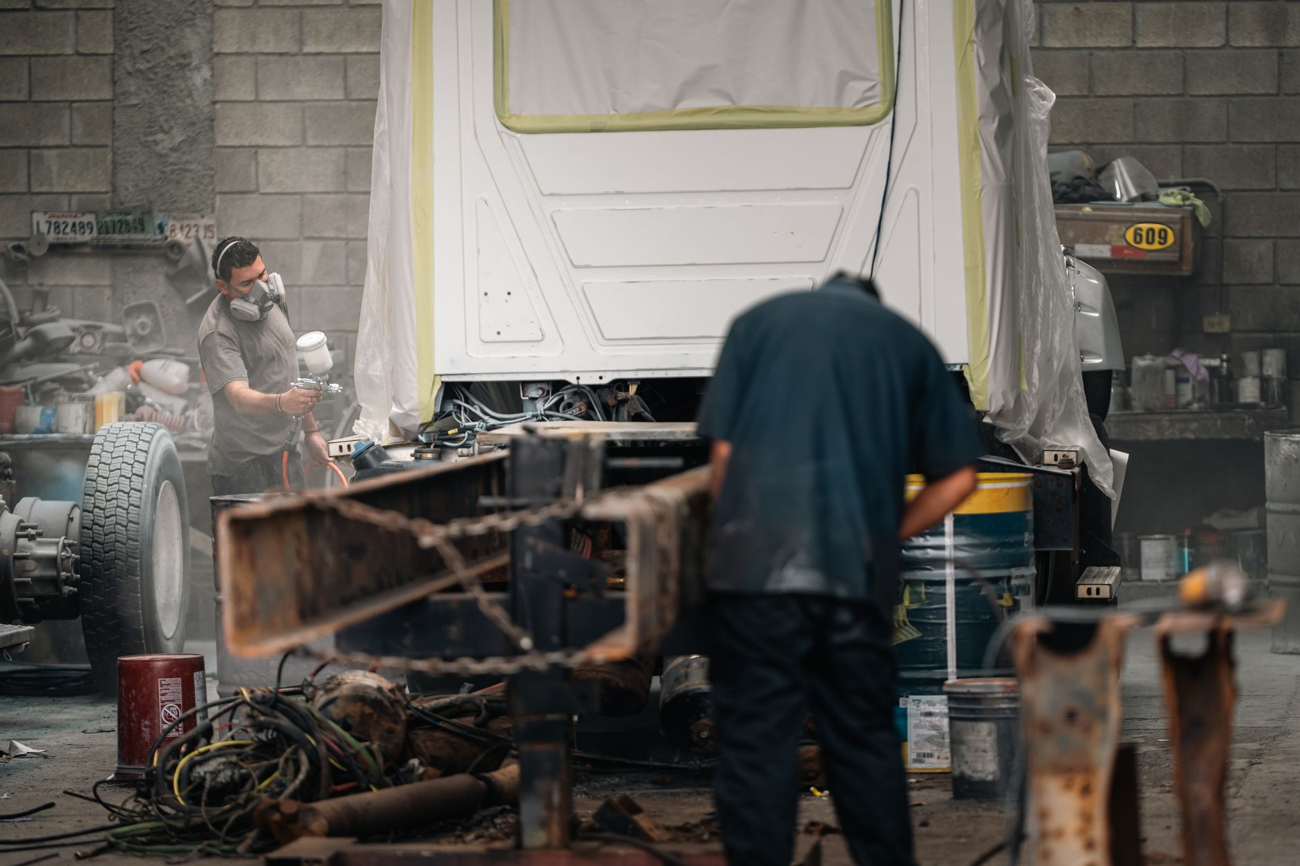 Automotive assembly workers handle vehicle components on a busy factory floor.