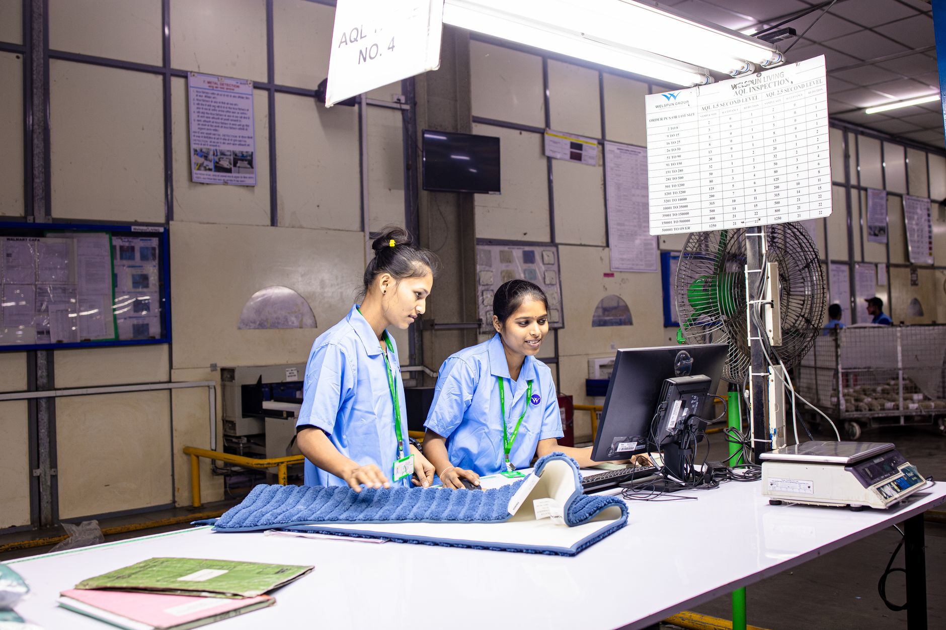 A manufacturing quality station where a worker handles precision components, echoing how labor was reassigned from repetitive feeding to higher-value work.
