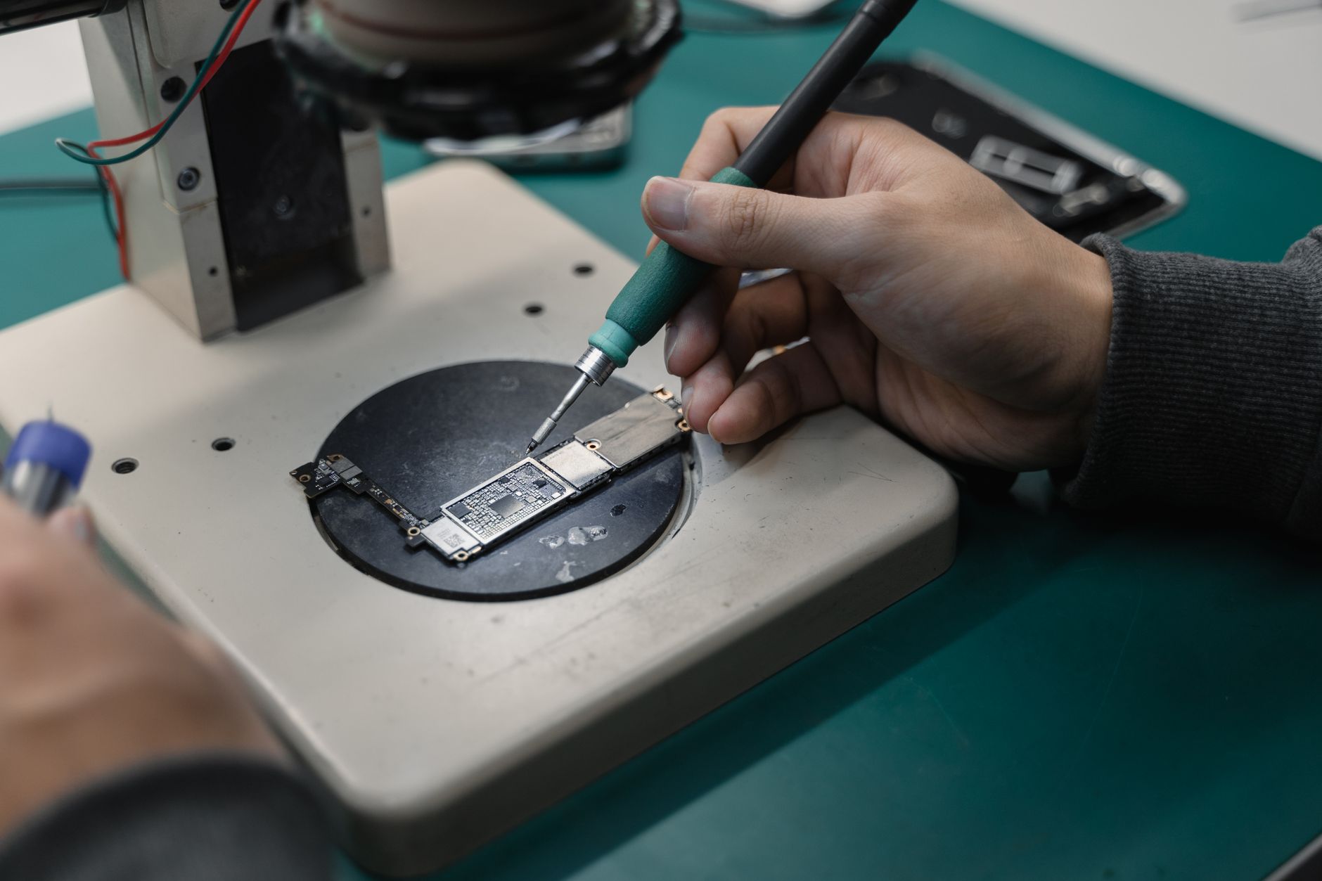 Technicians work at electronics assembly benches in a high-volume plant, reflecting the repetitive manual environment this cobot project improved.