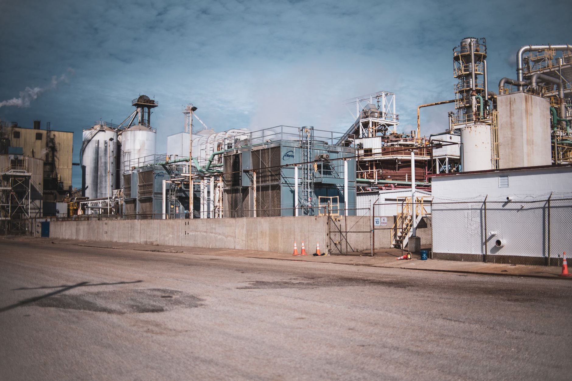 A modern industrial plant exterior with loading bays and employee parking.