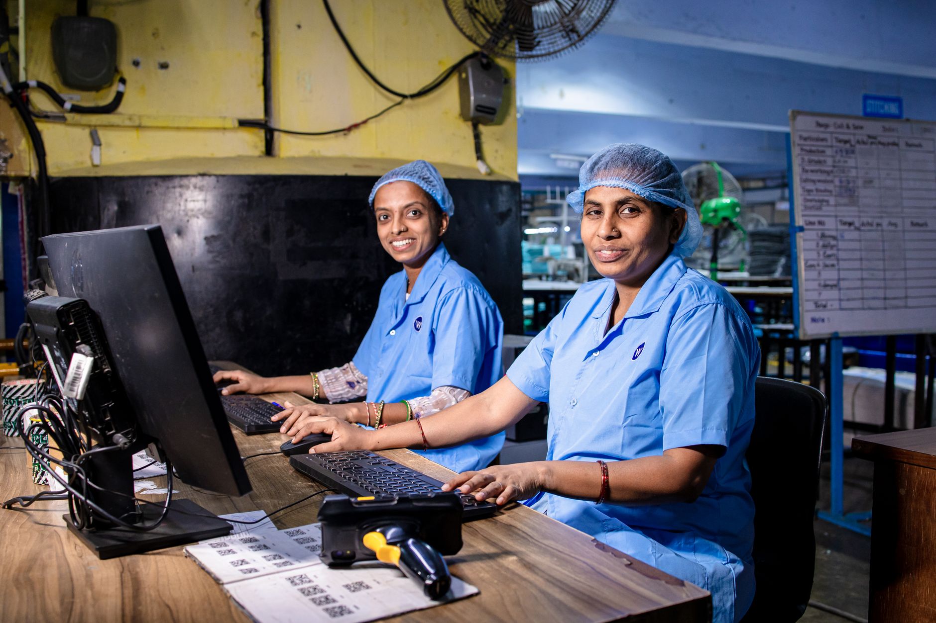 Technicians work along a bright electronics assembly production floor.