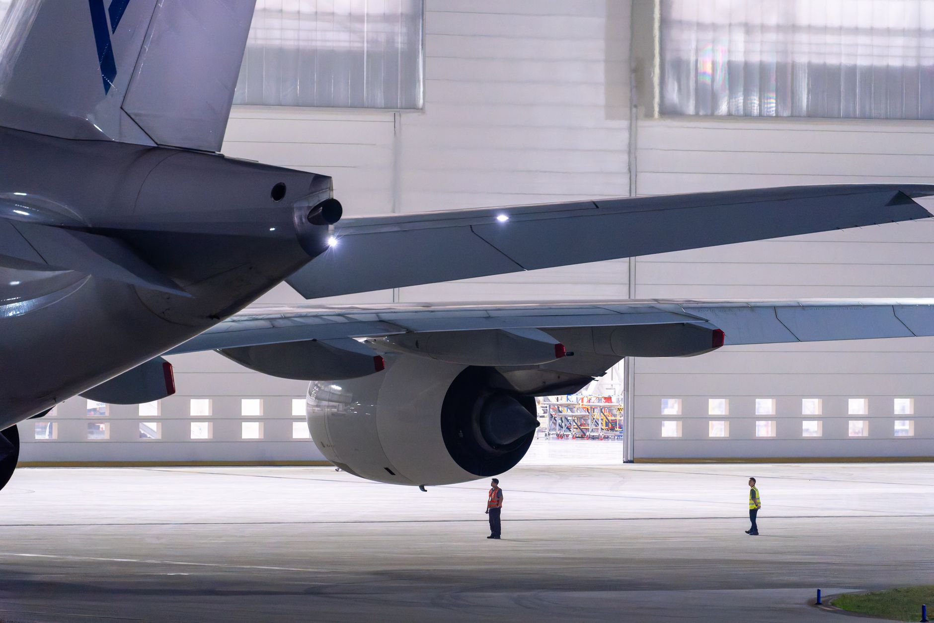 A maintenance technician closely inspects components inside a large aircraft engine.