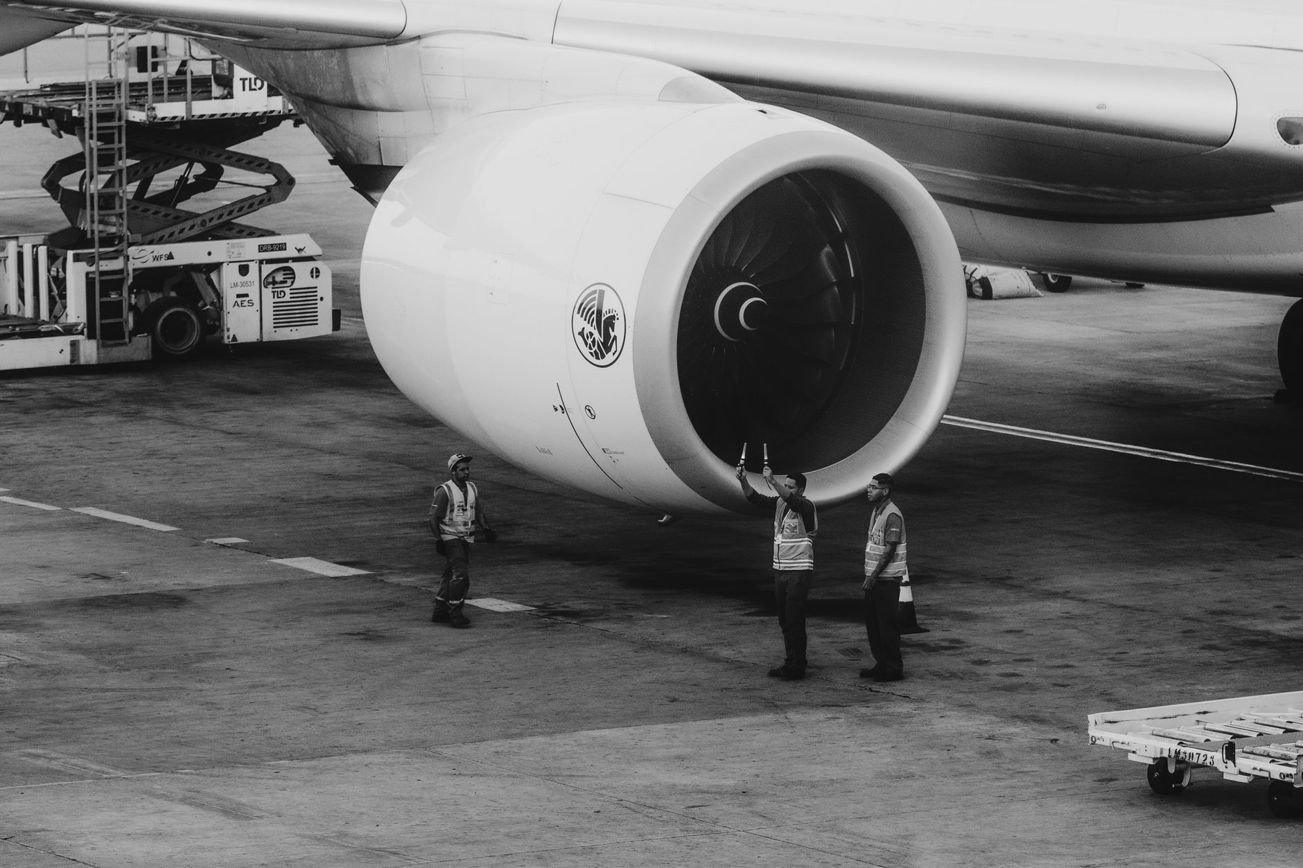 Aircraft maintenance professionals confer beside equipment in an aviation hangar.