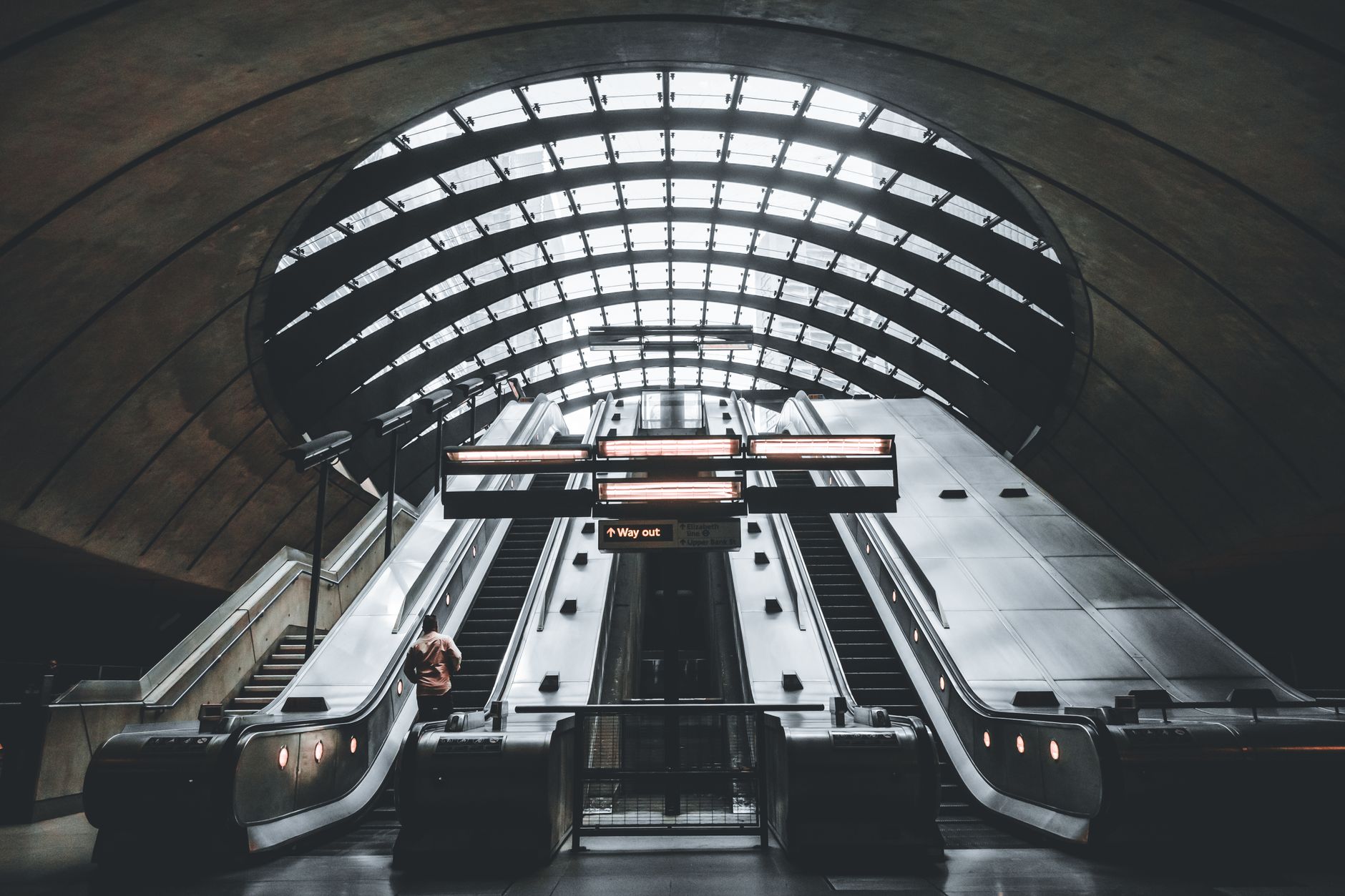 A sweeping stainless-steel escalator curves through a modern architectural interior.