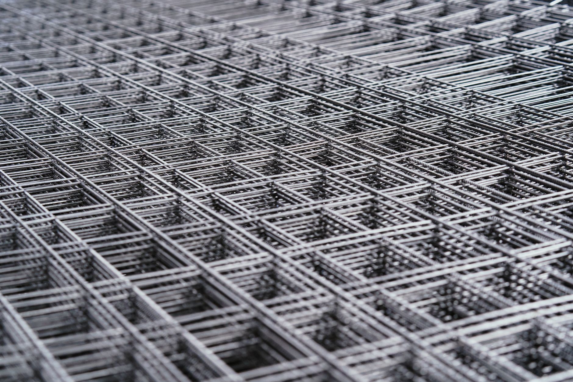 Rolls of fine knitted wire mesh stacked in an industrial textile plant.