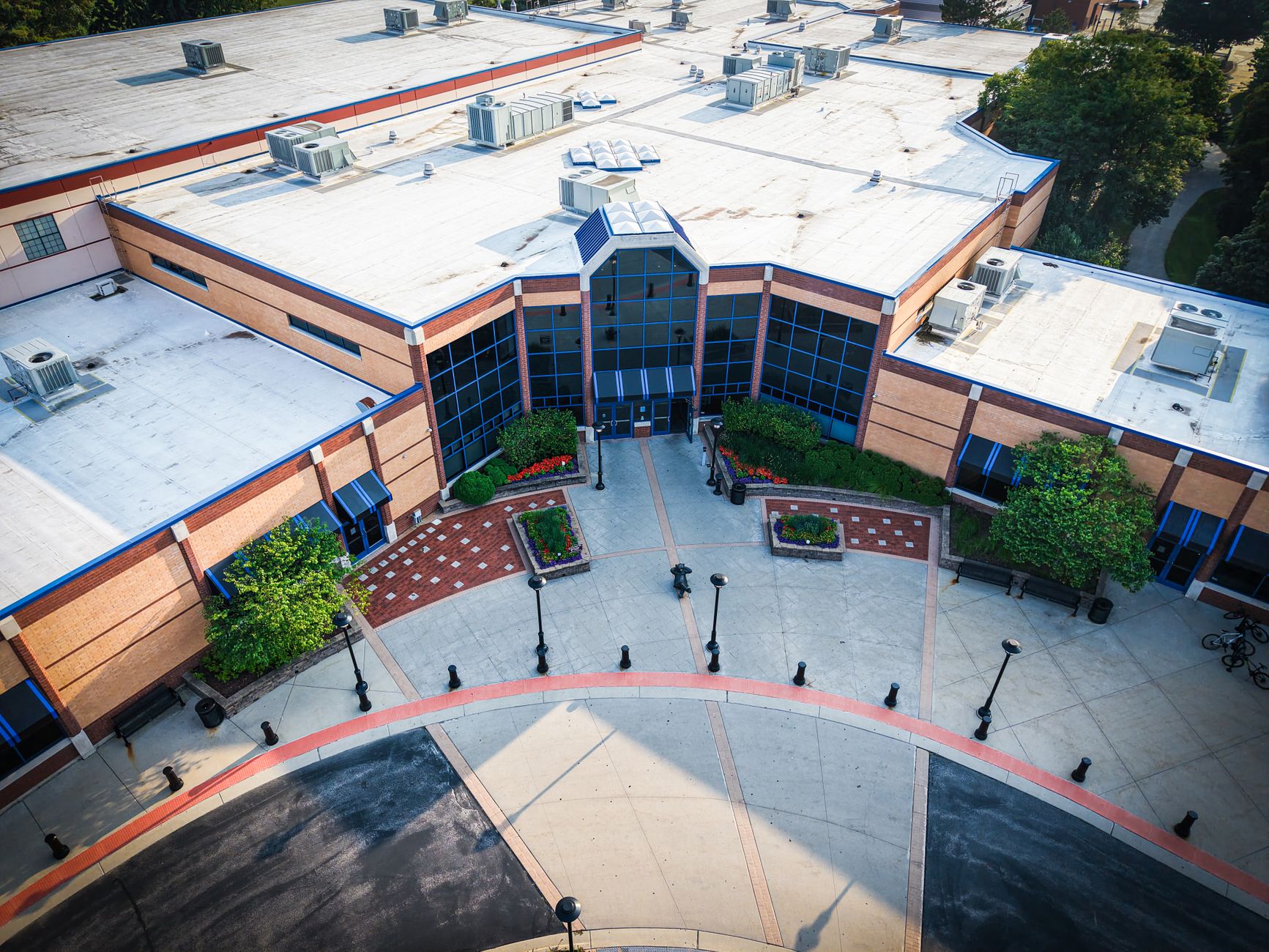 Employees cross a landscaped corporate campus courtyard during the workday.