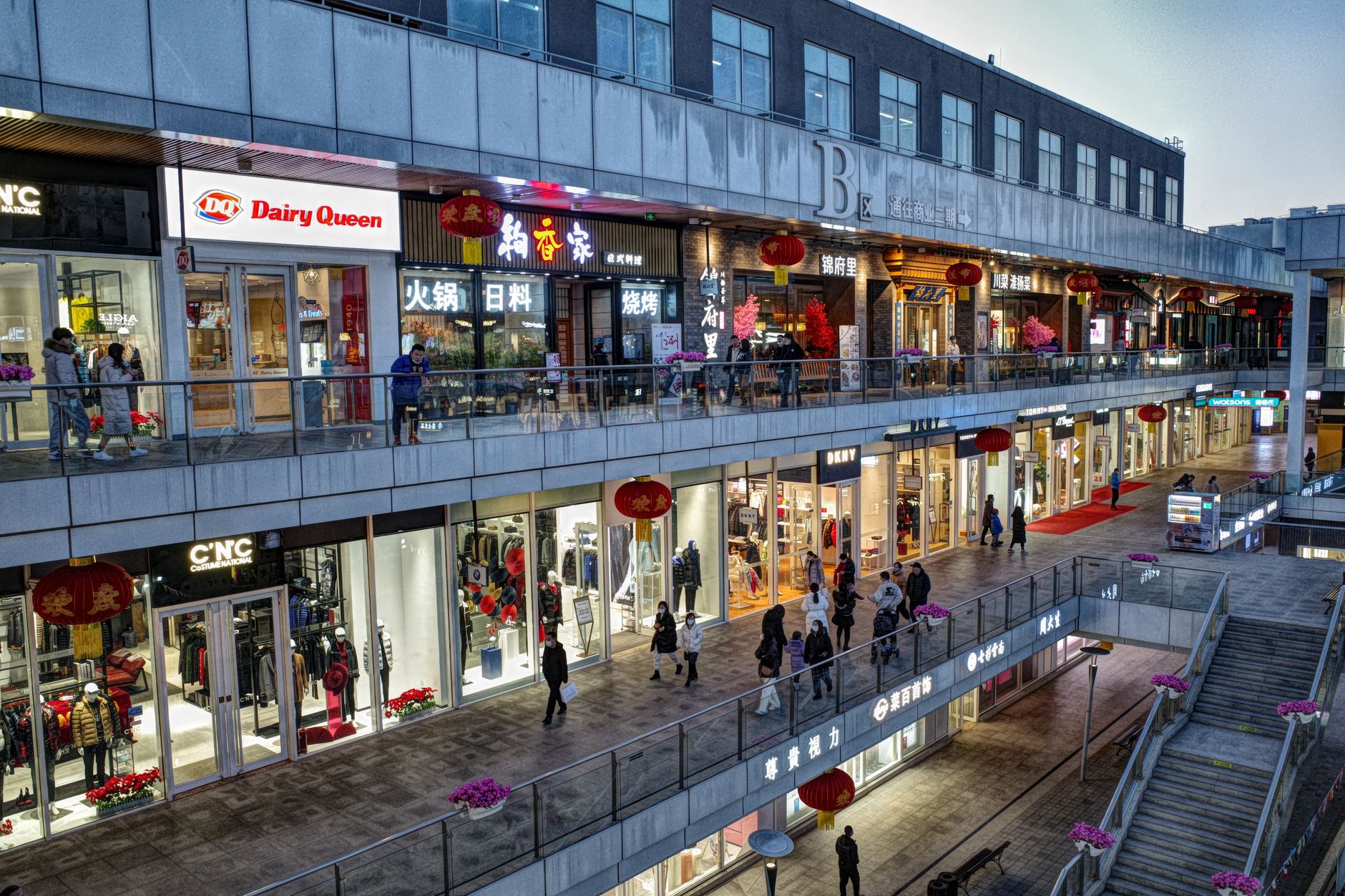 An illuminated outdoor shopping promenade stands quiet during late-night patrol hours.