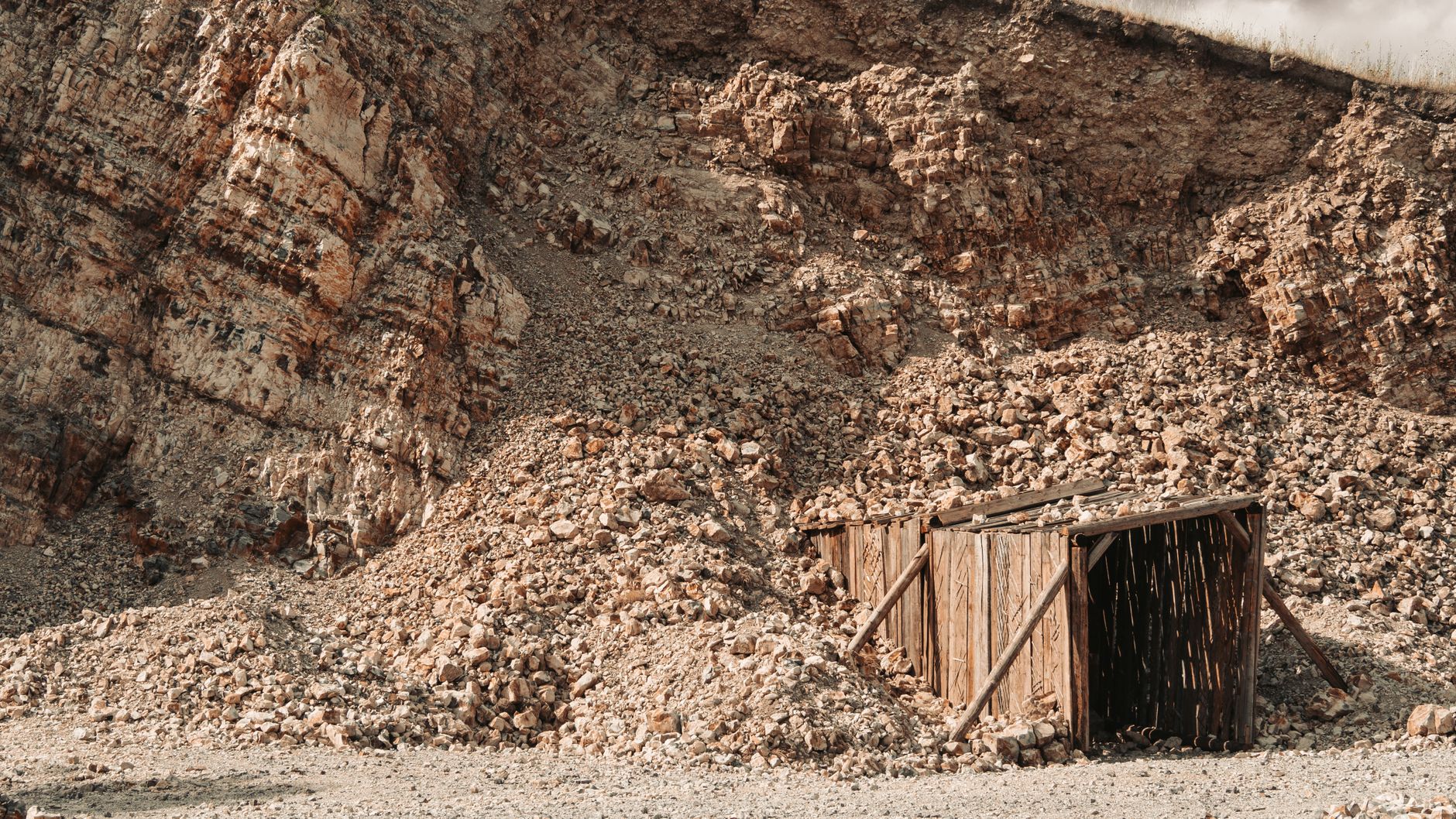A narrow underground passage with rough rock and a graded floor where loader cycles gain or lose minutes per tram.