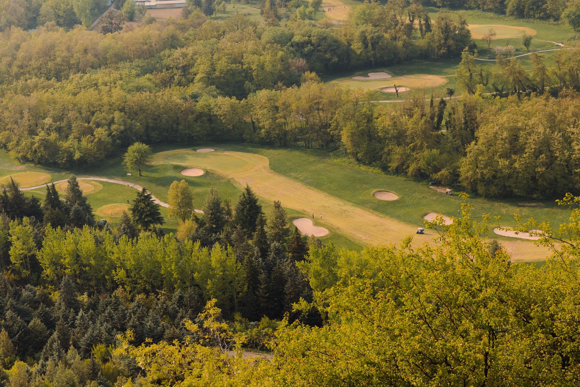 Aerial shot of a beautiful golf course surrounded by lush greenery and trees