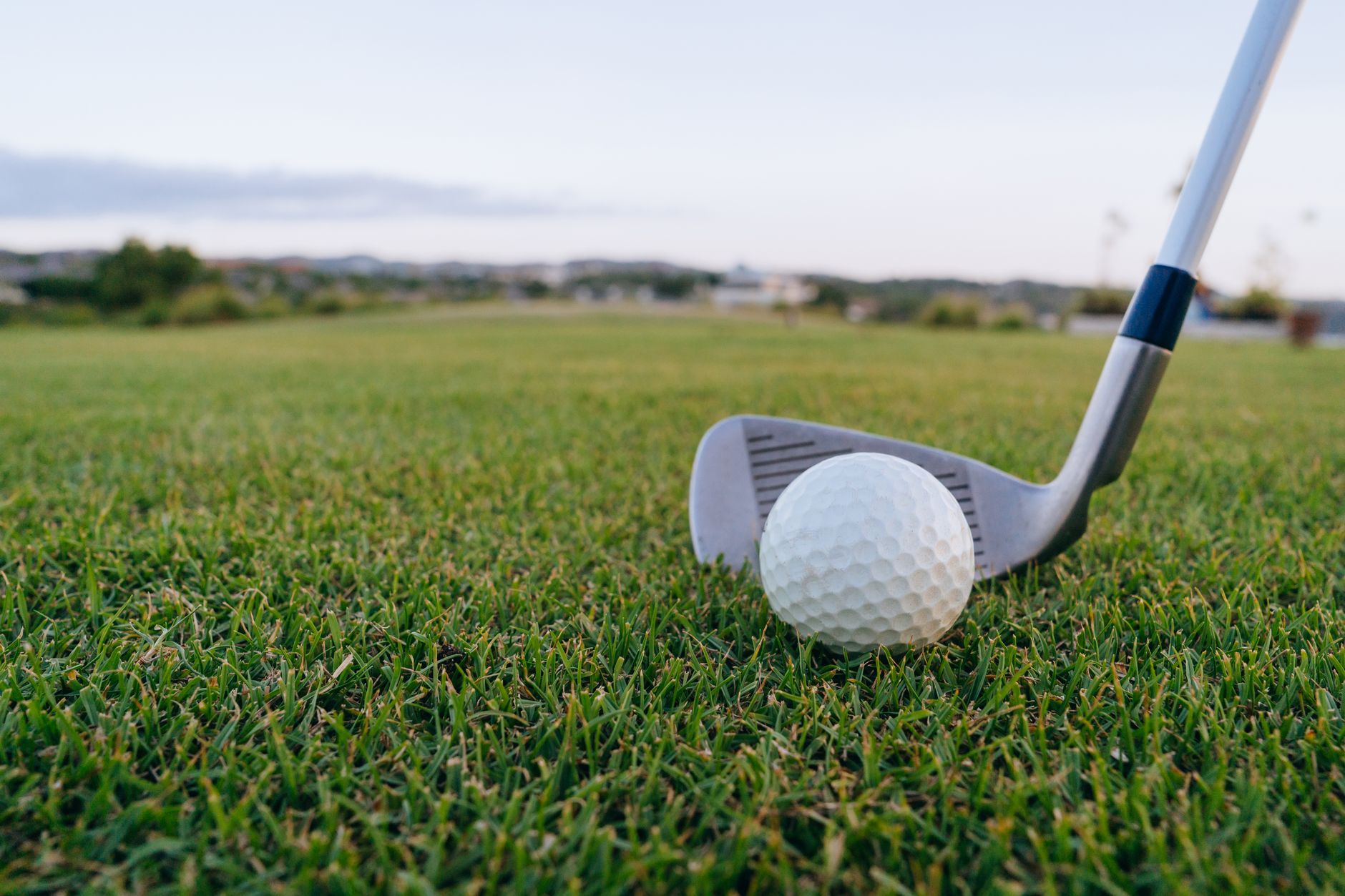 Golf ball with club on lush green grass, perfect for sports themes