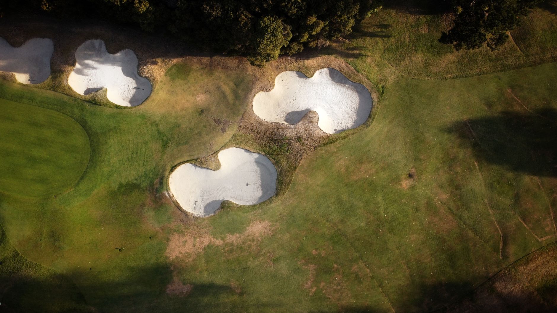 A stunning aerial shot capturing sand traps and green fields on a golf course during daytime