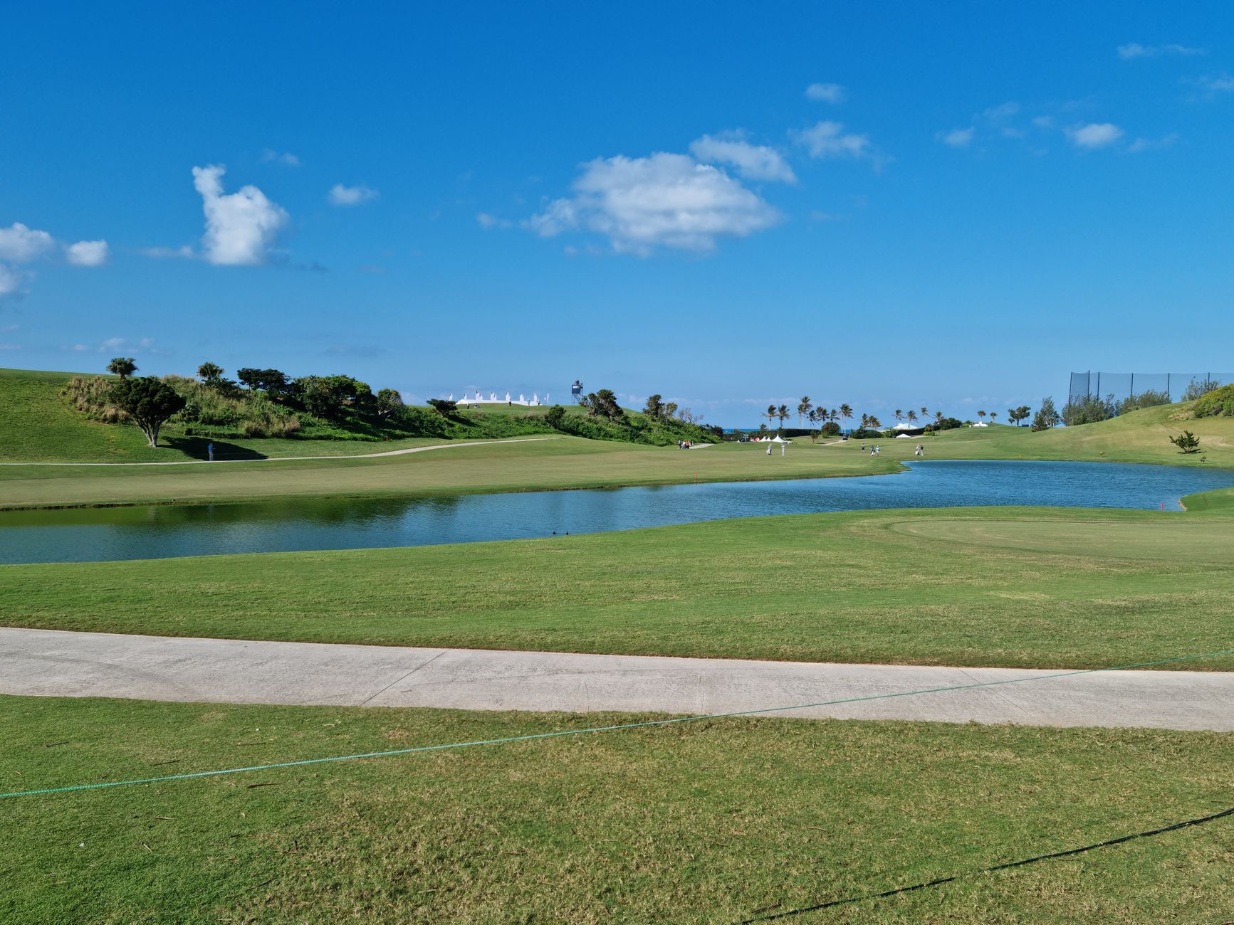 Serene view of a lush green golf course under a bright blue sky with picturesque clouds