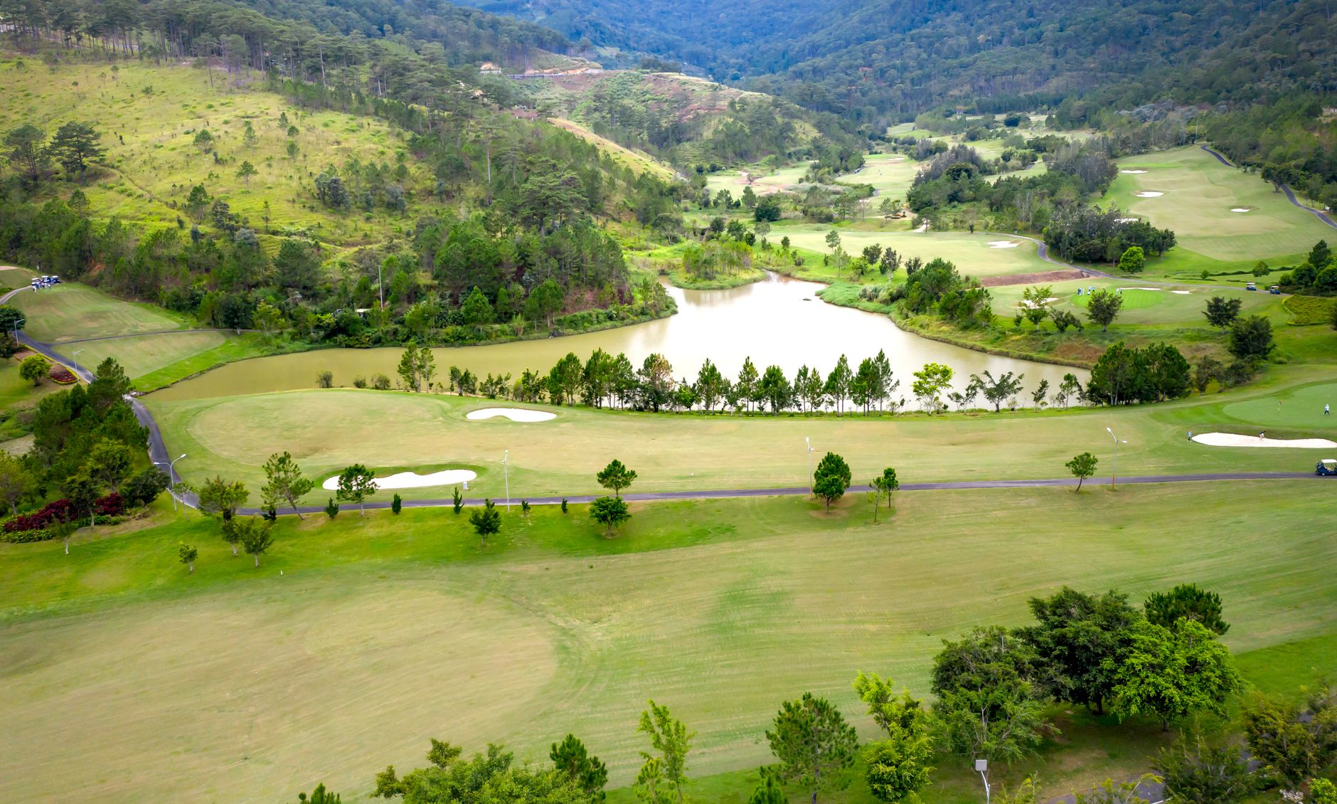 Aerial view of a lush green golf course surrounded by hills and trees