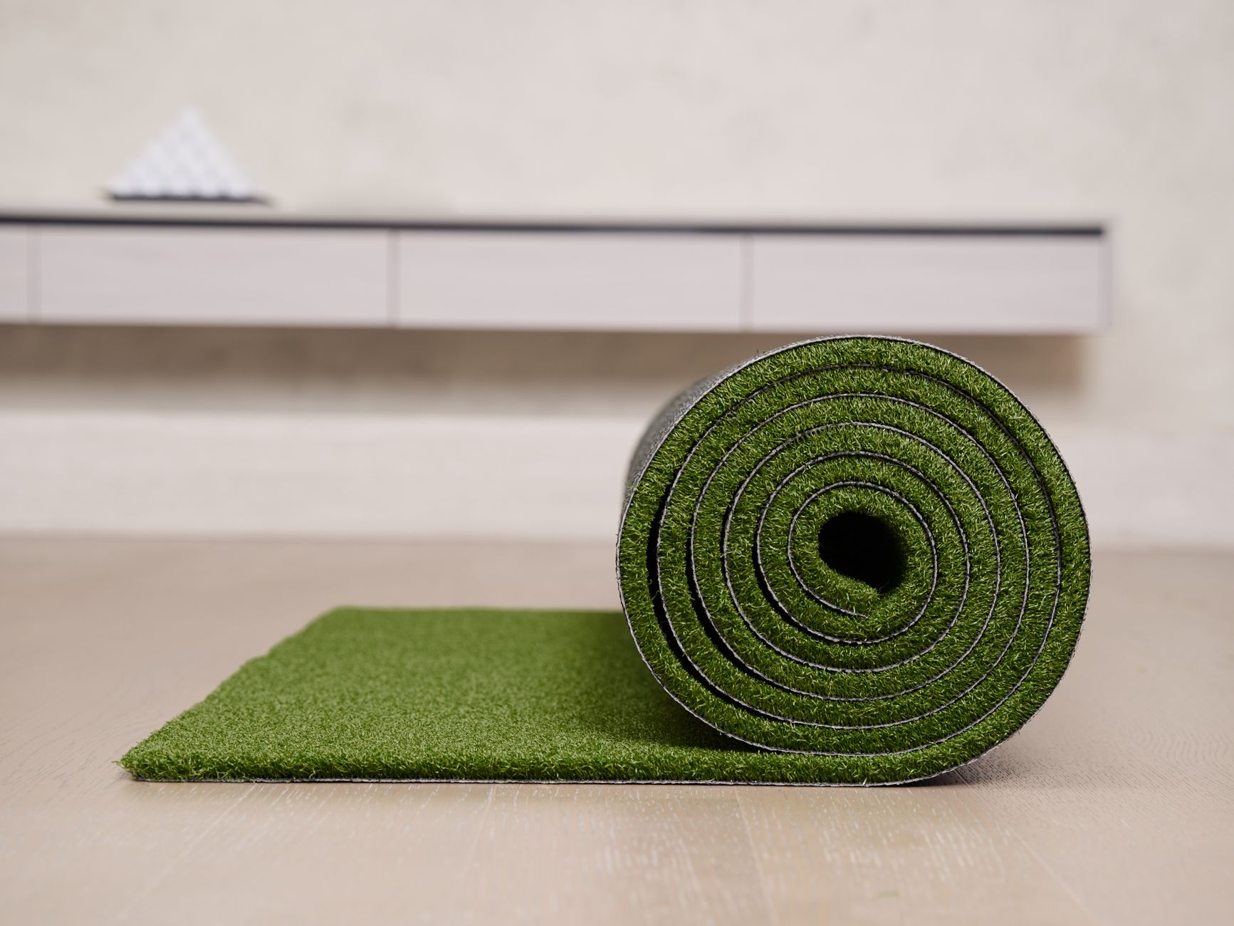 Close-up of a rolled artificial turf mat on a floor, ideal for indoor golf practice