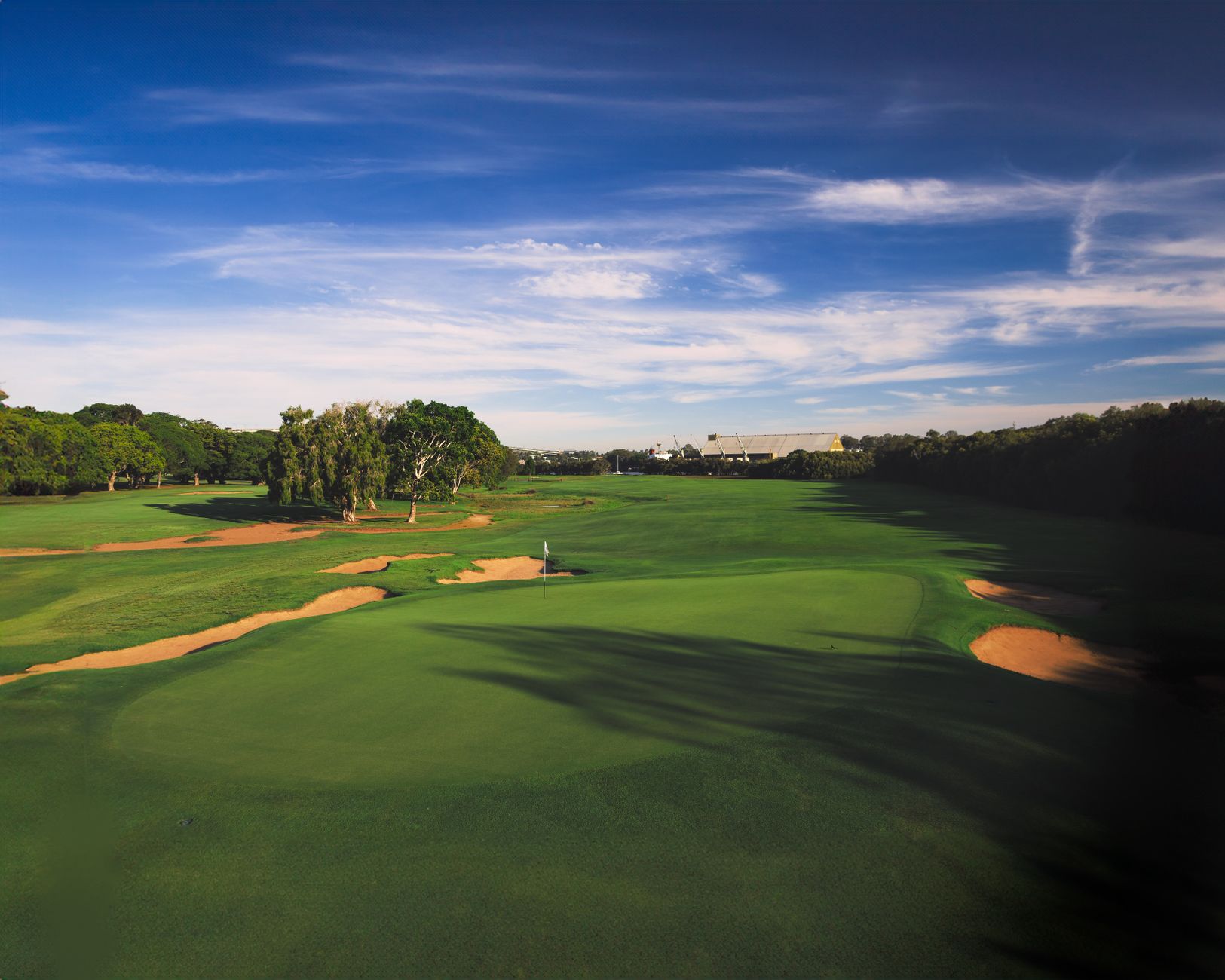 Aerial view of a lush green golf course under a blue sky, perfect for outdoor sports enthusiasts
