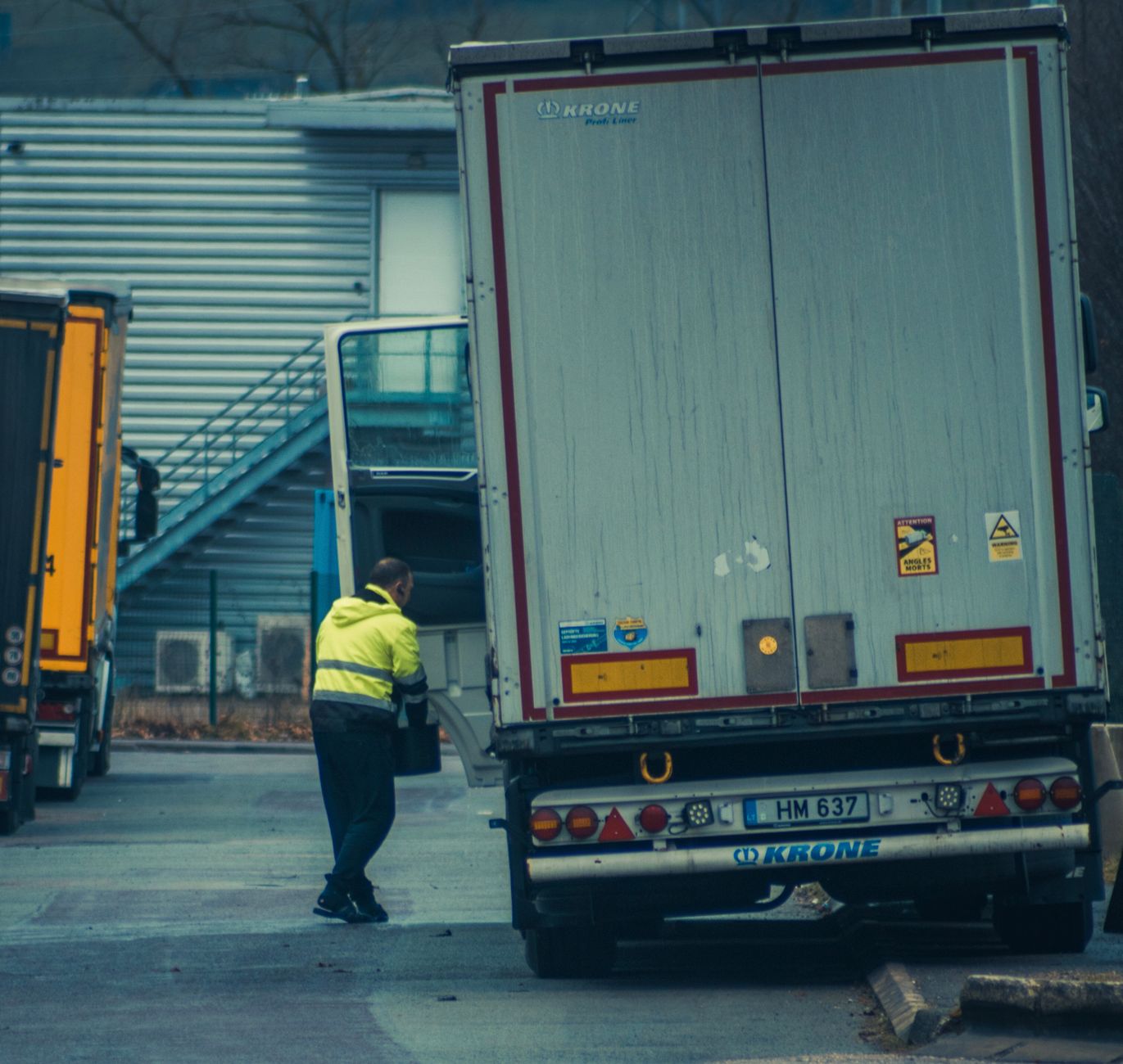 Workers at a warehouse dock unloading cartons from an open trailer.