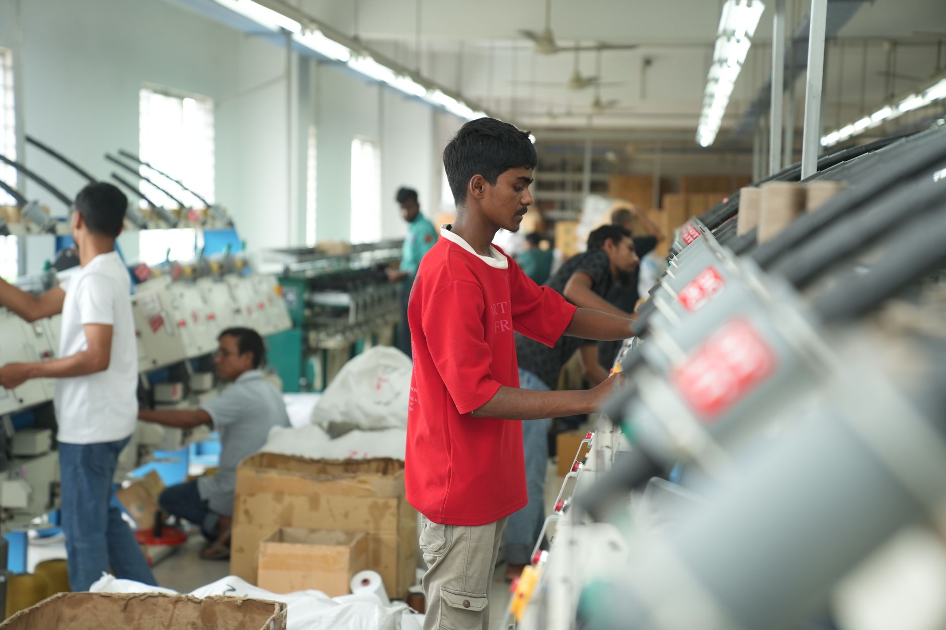 Factory workers in high-visibility vests walking through an industrial production area during a shift.