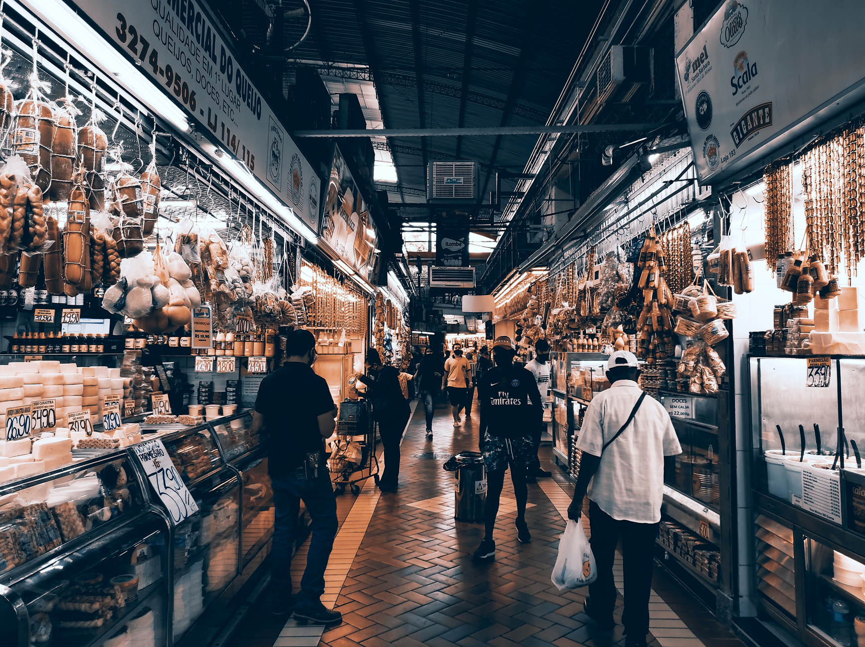 A long aisle in a big-box retail store at night, with tall shelves stacked with boxed products under bright ceiling lights.