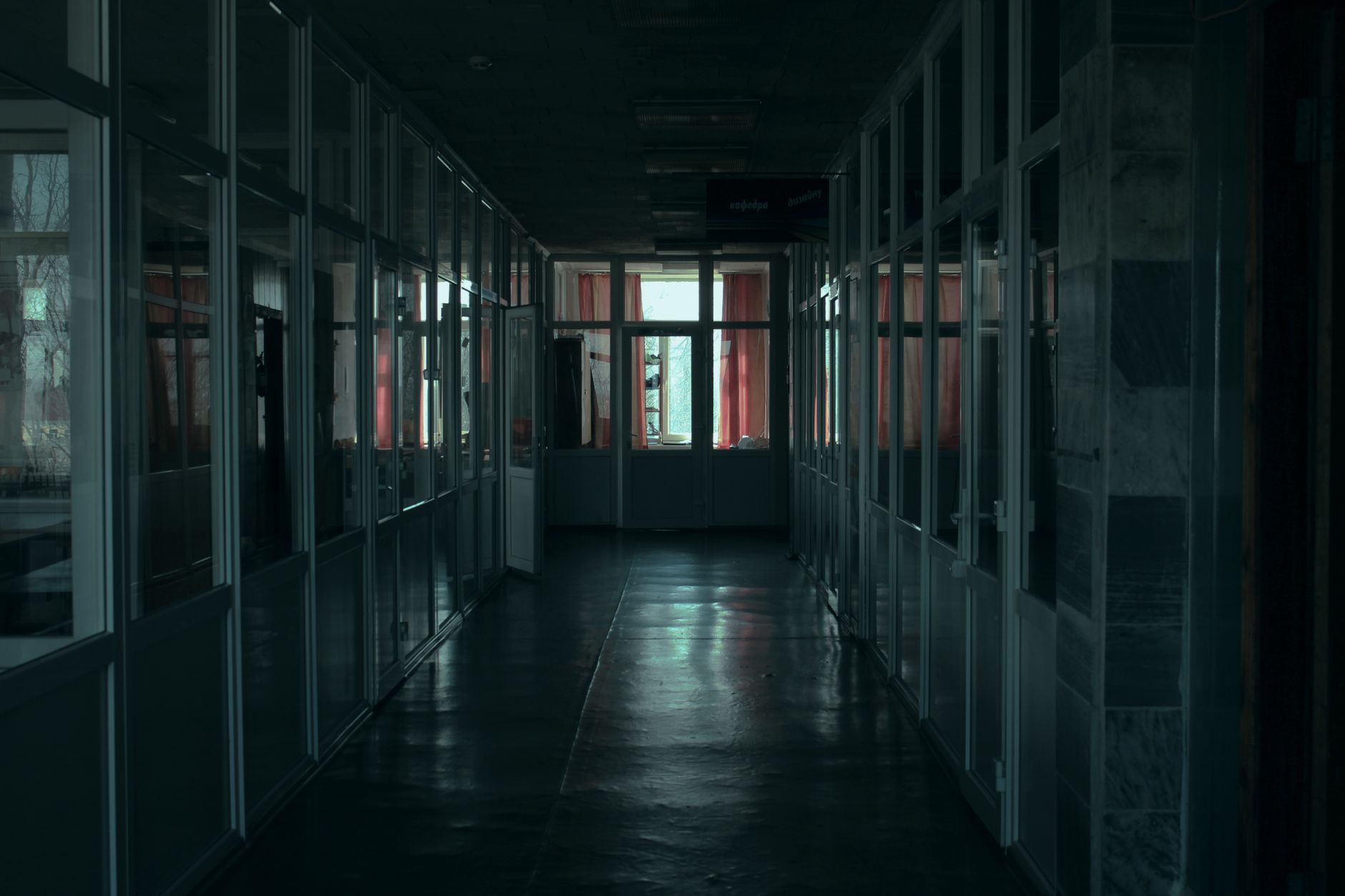 An empty wide office corridor with polished hard floors under overhead lights.