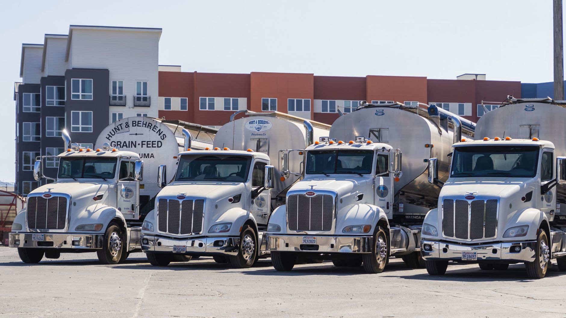 Open industrial yard beside a factory building with trucks parked for loading.