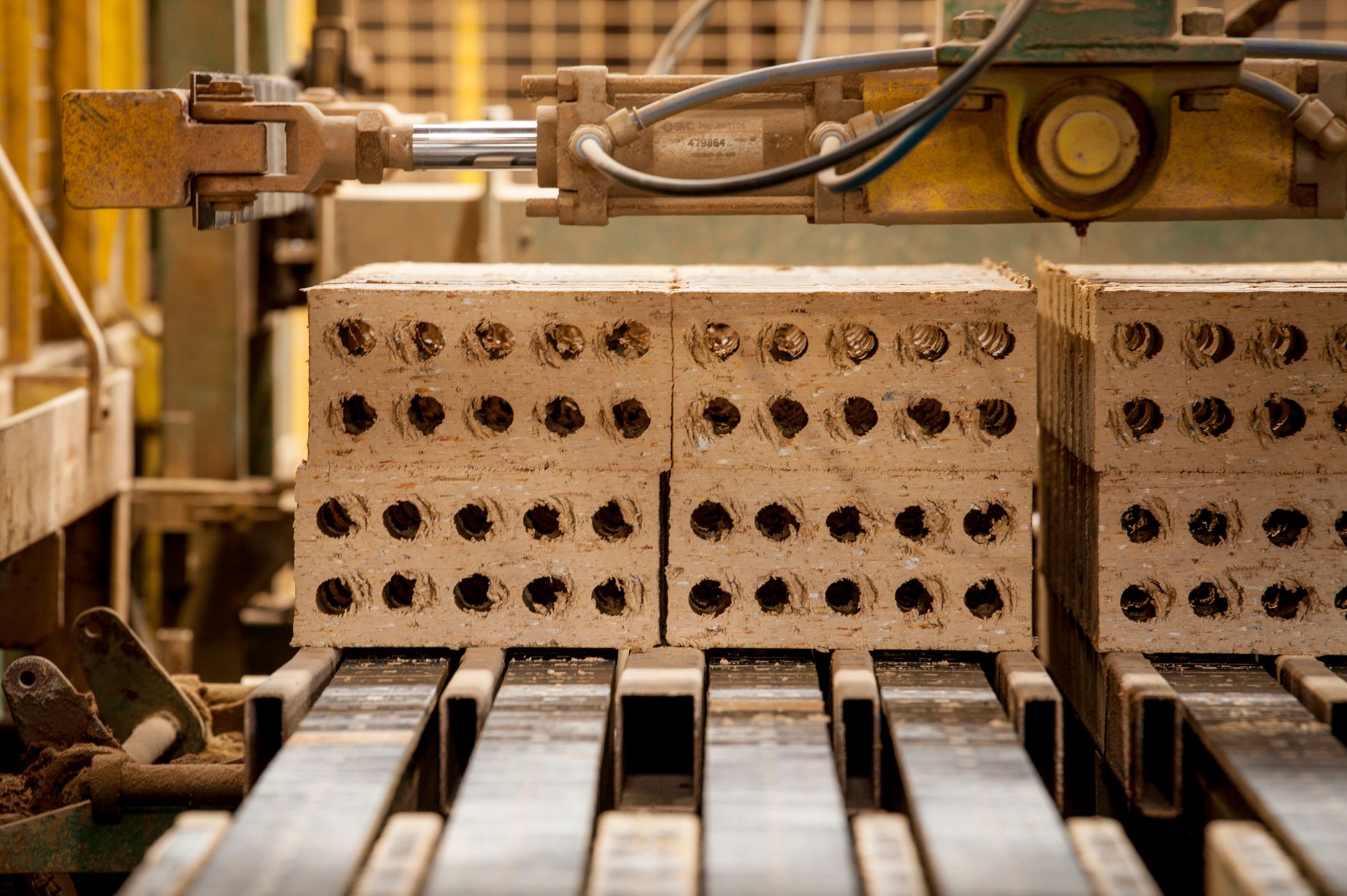 Wide view of a brick manufacturing plant with kilns and stacked finished brick under open sky.