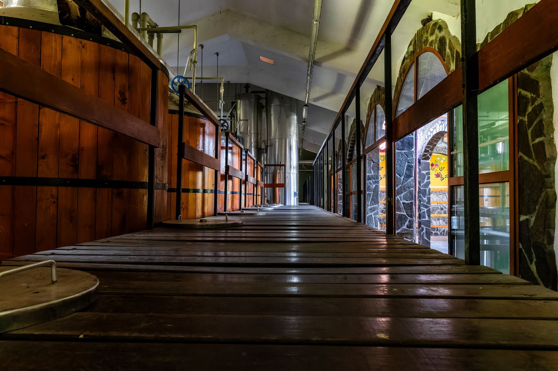 Stainless steel brewing vessels and pipework fill a busy brewhouse floor.