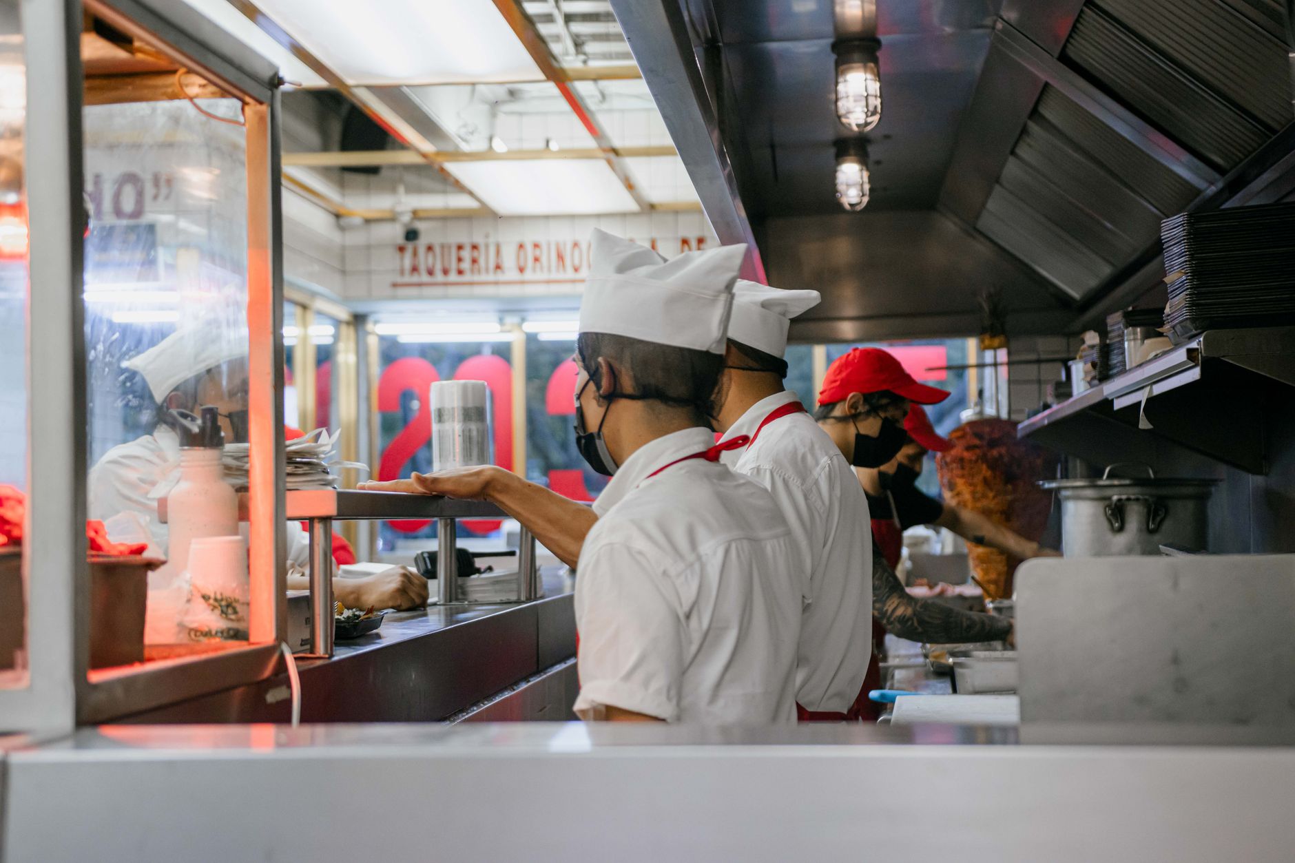 Cooks and kitchen staff working at a busy commercial kitchen during dinner service.