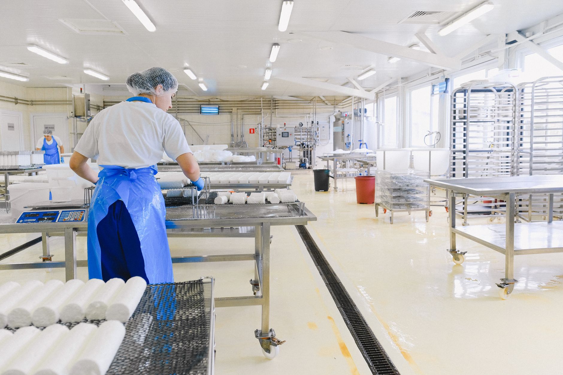 A food plant production floor being cleaned, with wet surfaces and hygienic stainless steel areas that call for washdown.