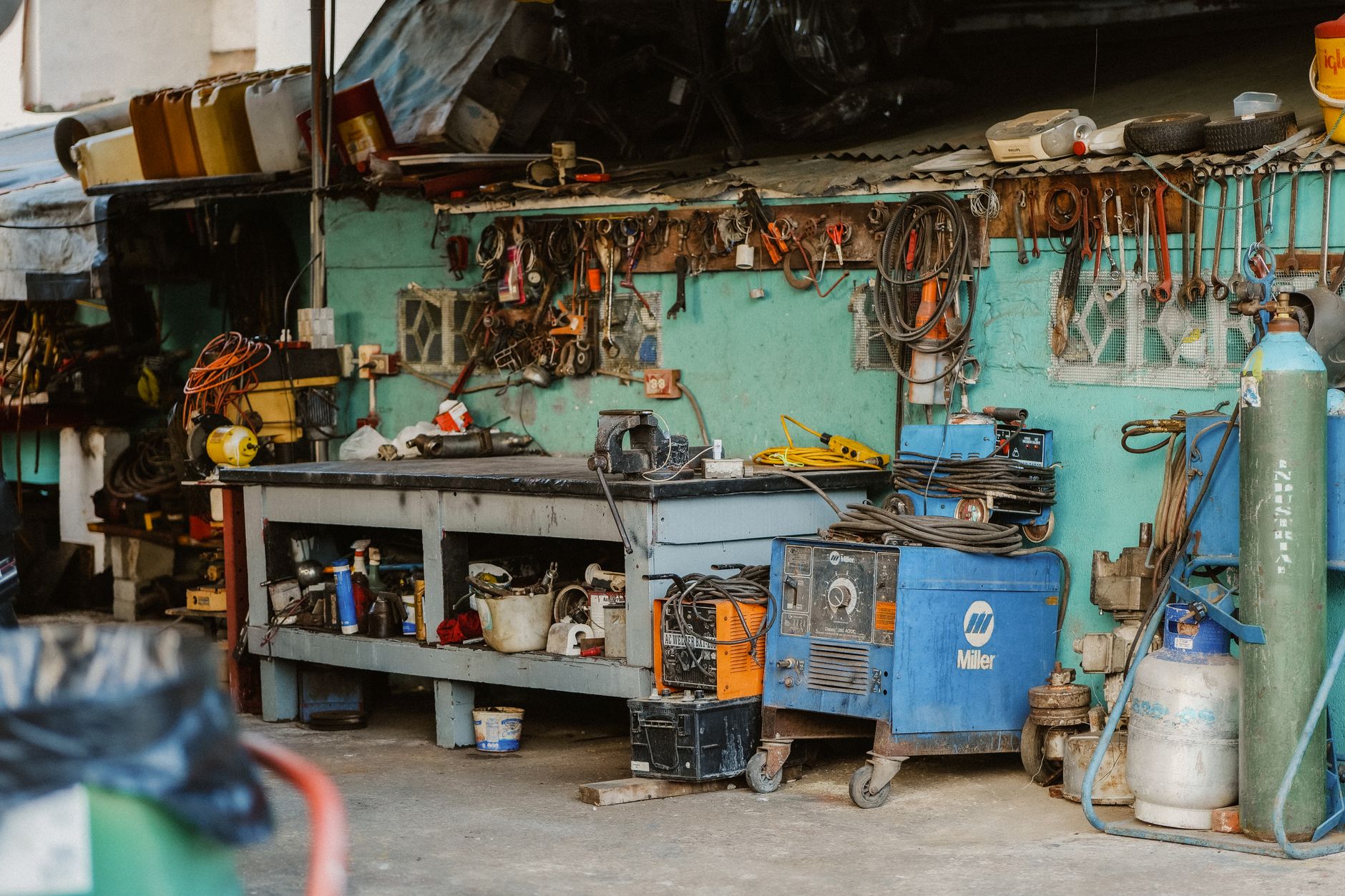 Hand tools and parts laid out on a workbench in a garage repair shop.