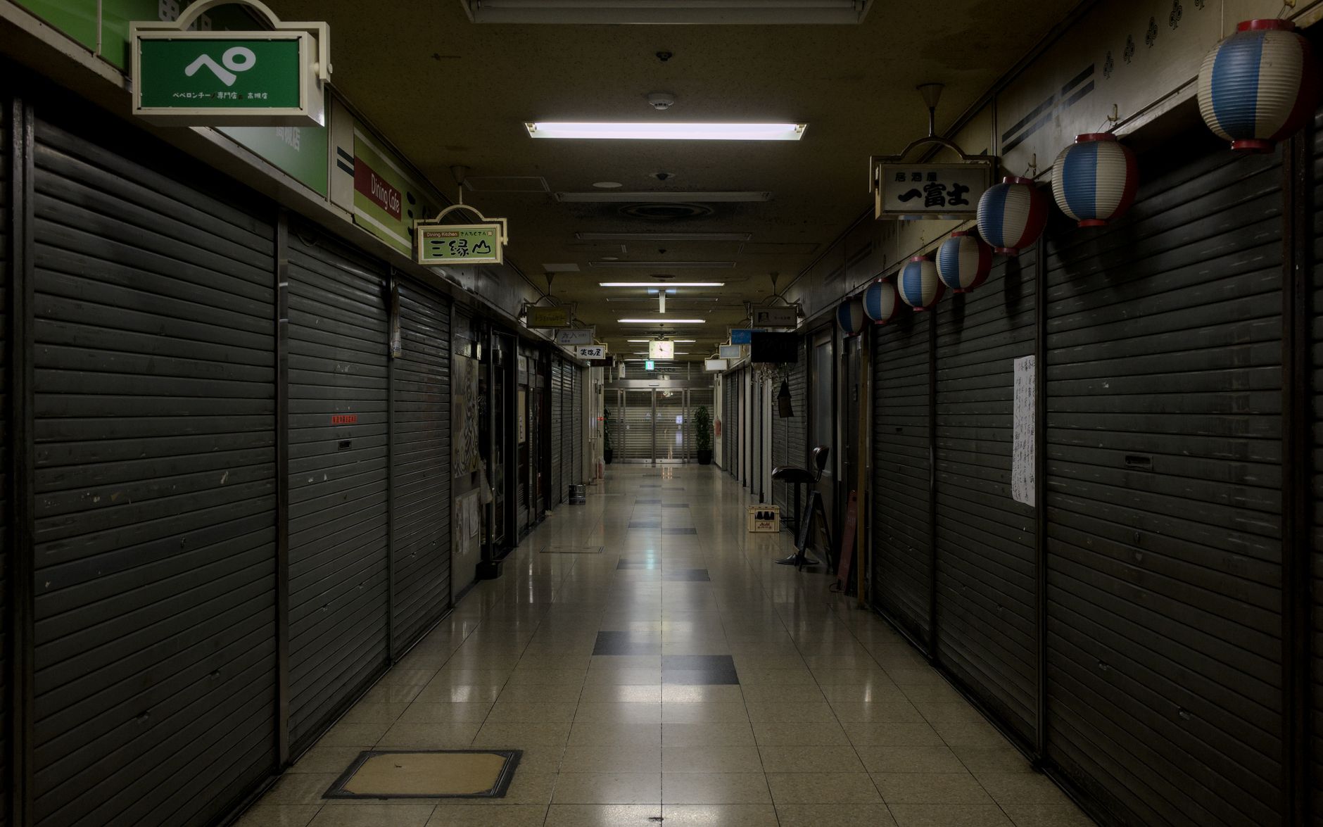 An empty office corridor after hours with overhead lights on a freshly maintained floor.