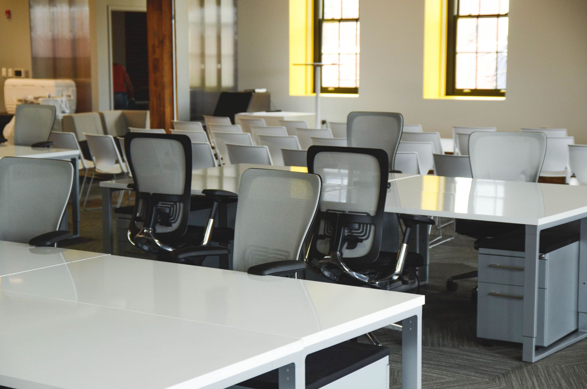 Members sit at communal desks in a coworking space with clean, uncluttered floors.
