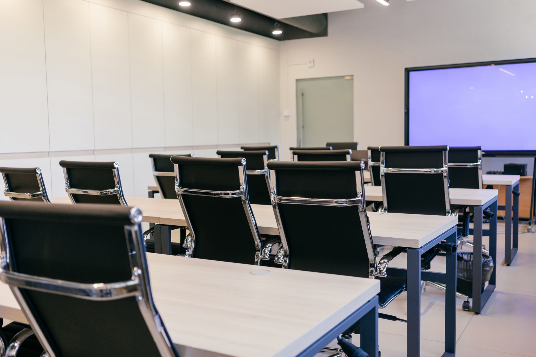 An empty meeting room with a long table and chairs in a modern shared office building.