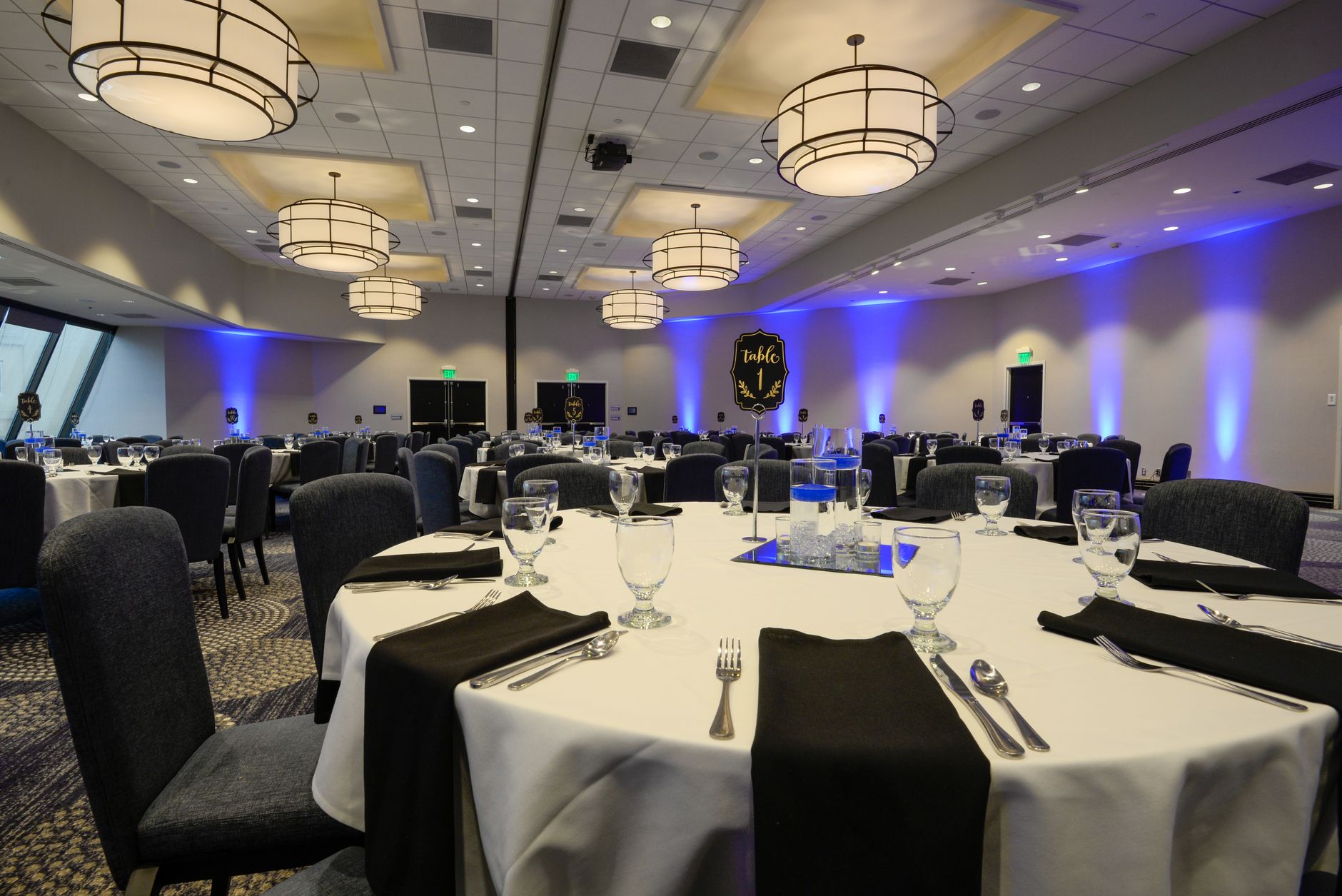 A large hotel ballroom set up with round banquet tables and chairs ready for an event.
