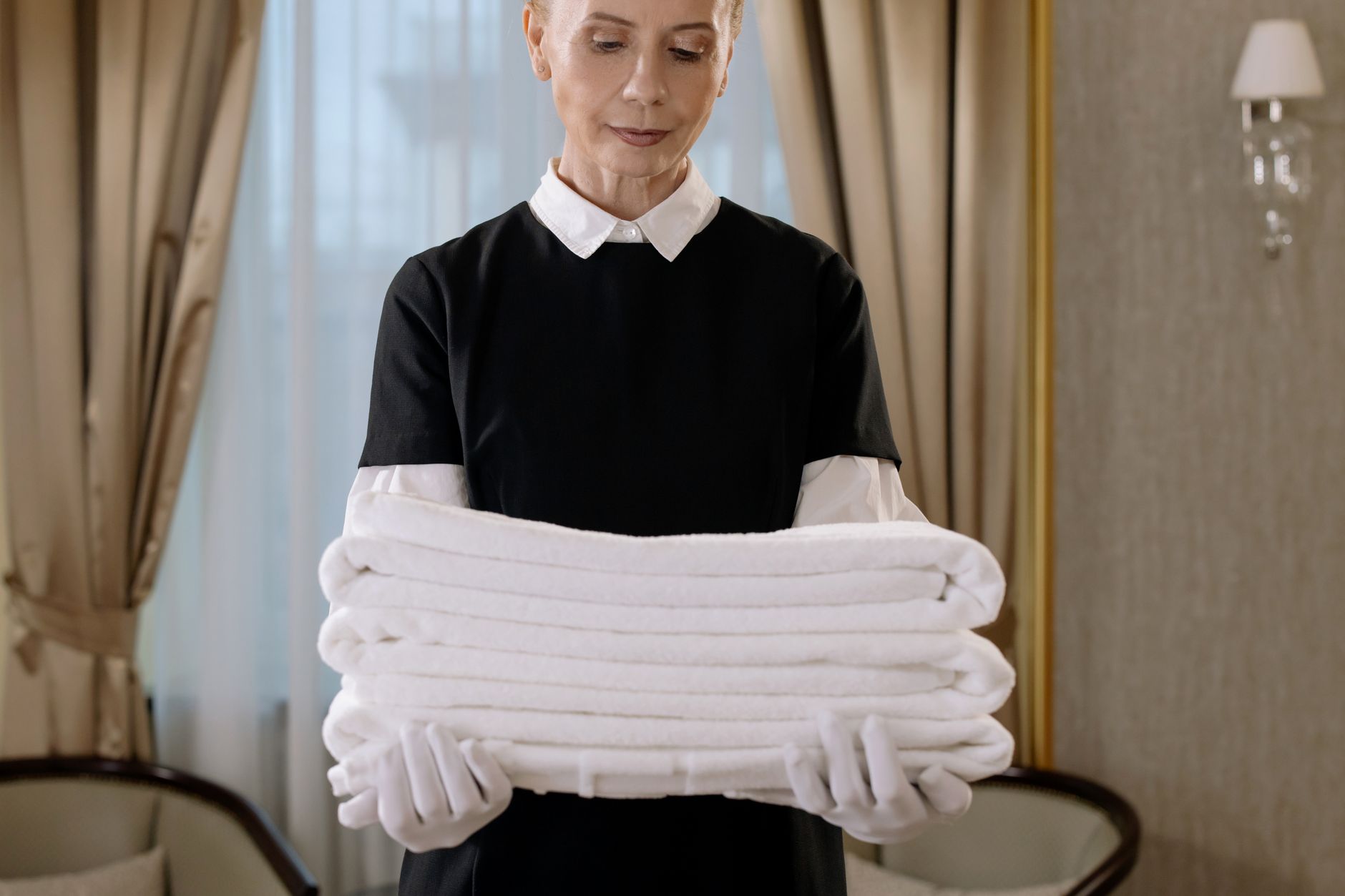 A housekeeping cart with cleaning supplies beside a hotel hallway, showing the hands-on work that remains with staff.