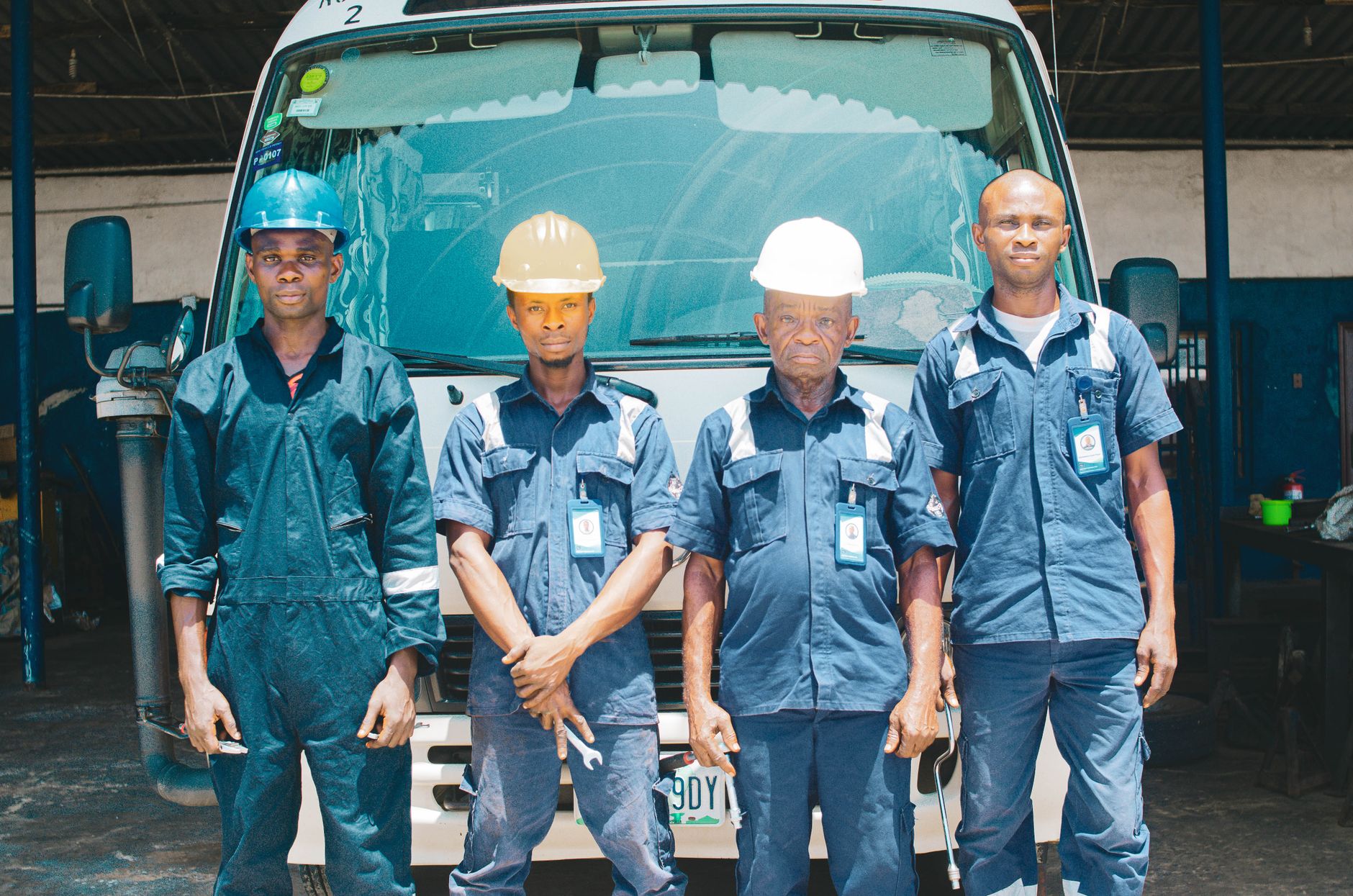 Close view of facility maintenance workers in work clothes standing near a cleaning cart in a building corridor.