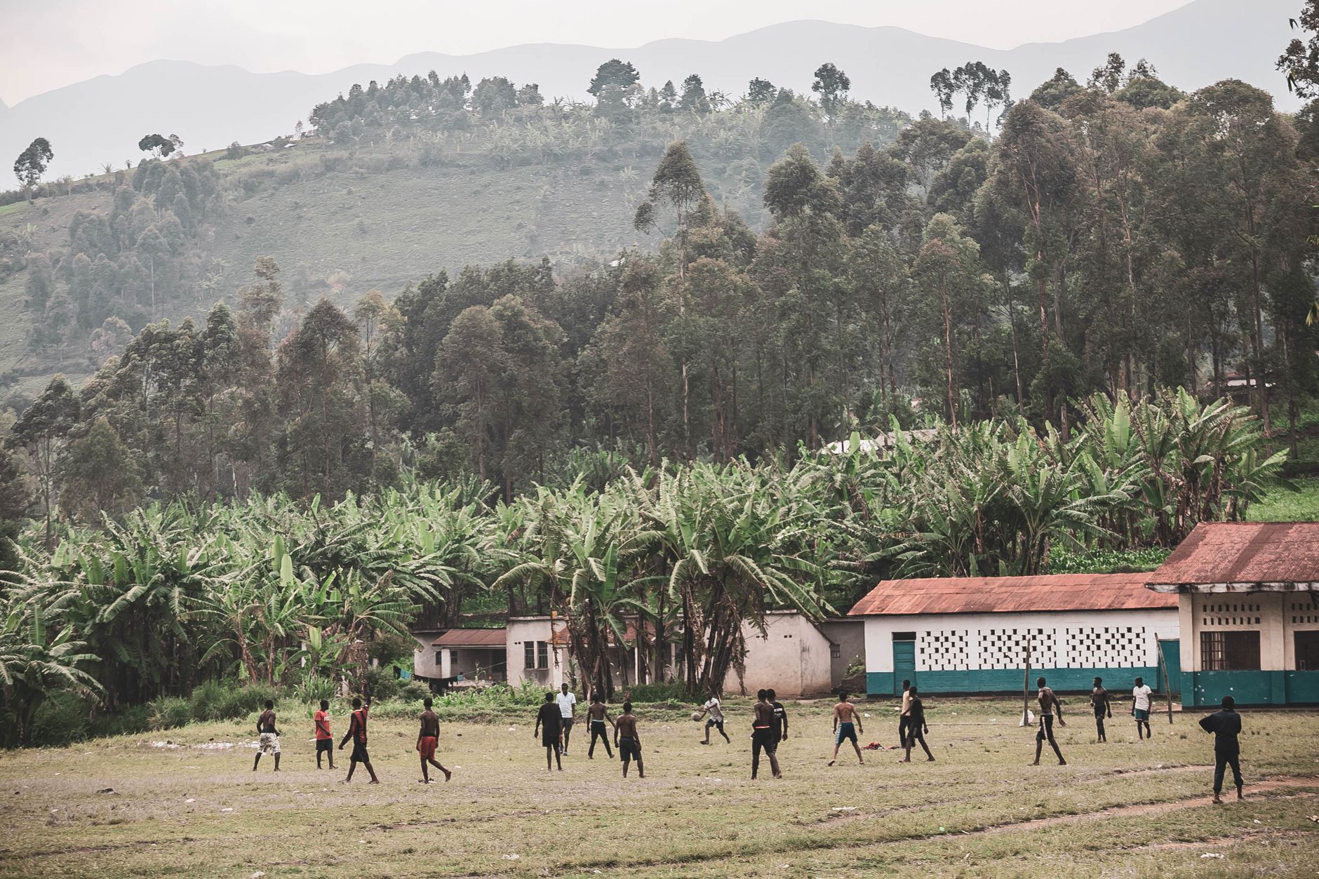 An open school playing field with striped green grass and a low fence line, ready for practice.
